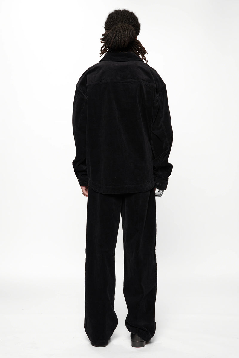 View from the back of a person wearing a Vintage Black Corduroy Float Overshirt with black pants and shoes on a white background