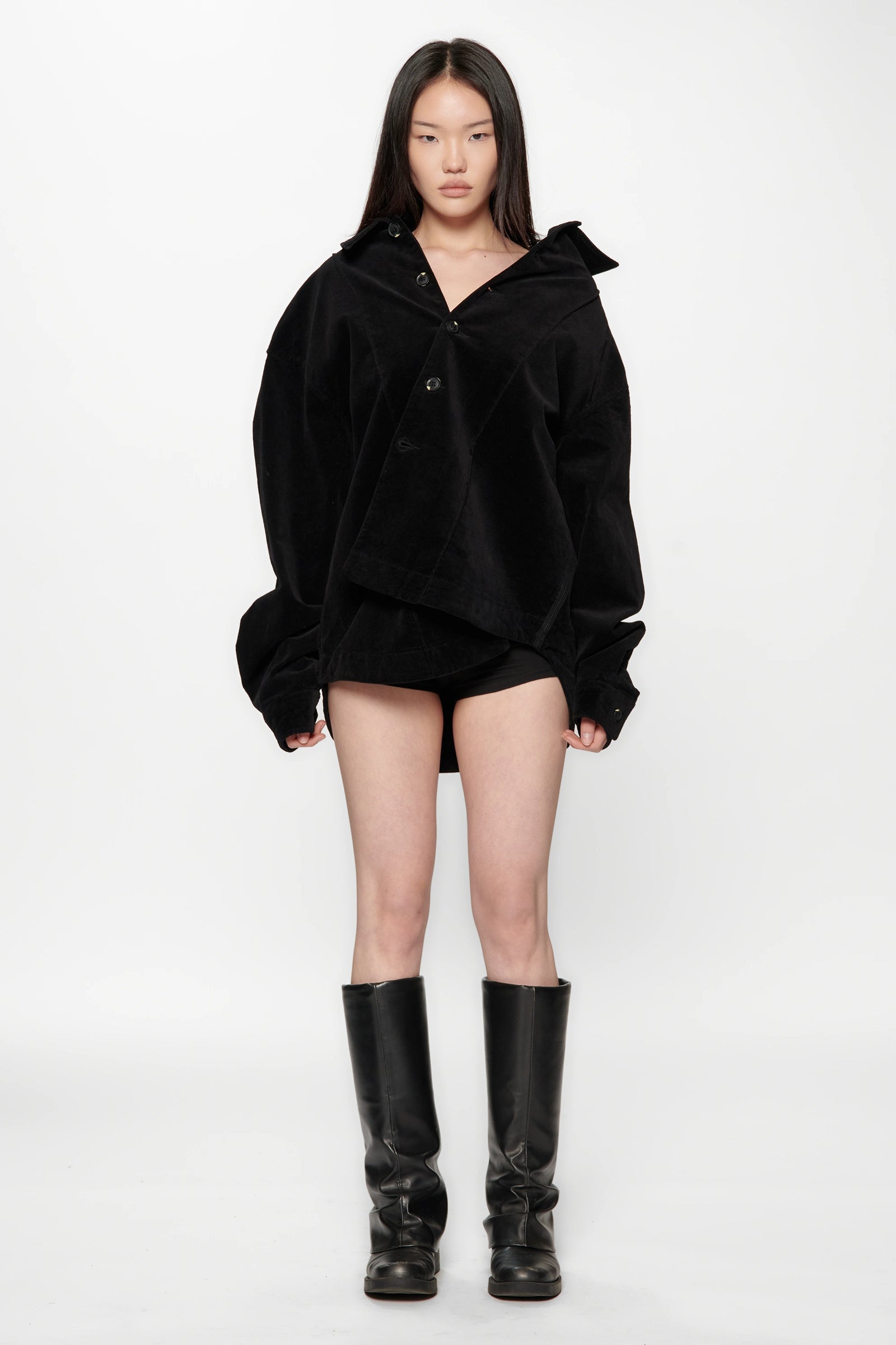 A female model wearing a Vintage Black Corduroy Float Overshirt with knee-high boots on a white background
