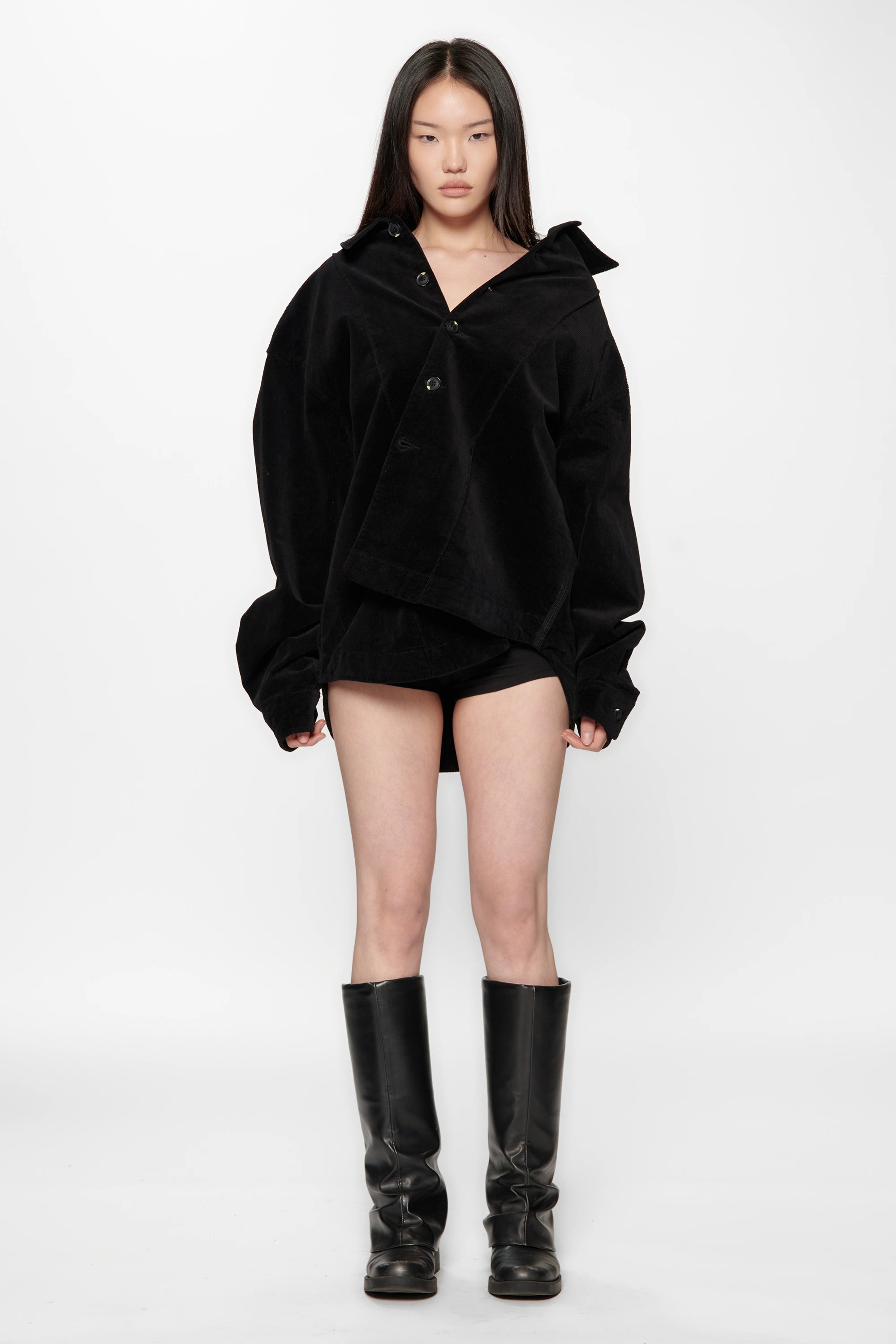 A female model wearing a Vintage Black Corduroy Float Overshirt with knee-high boots on a white background
