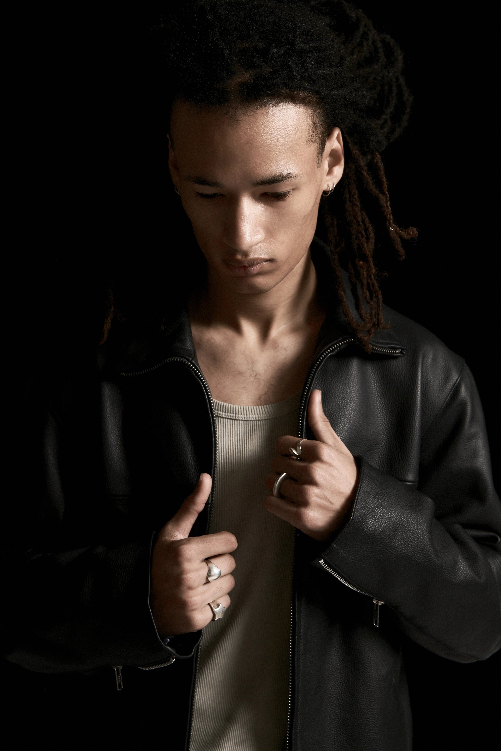 Person wearing a dark leather jacket against a black background