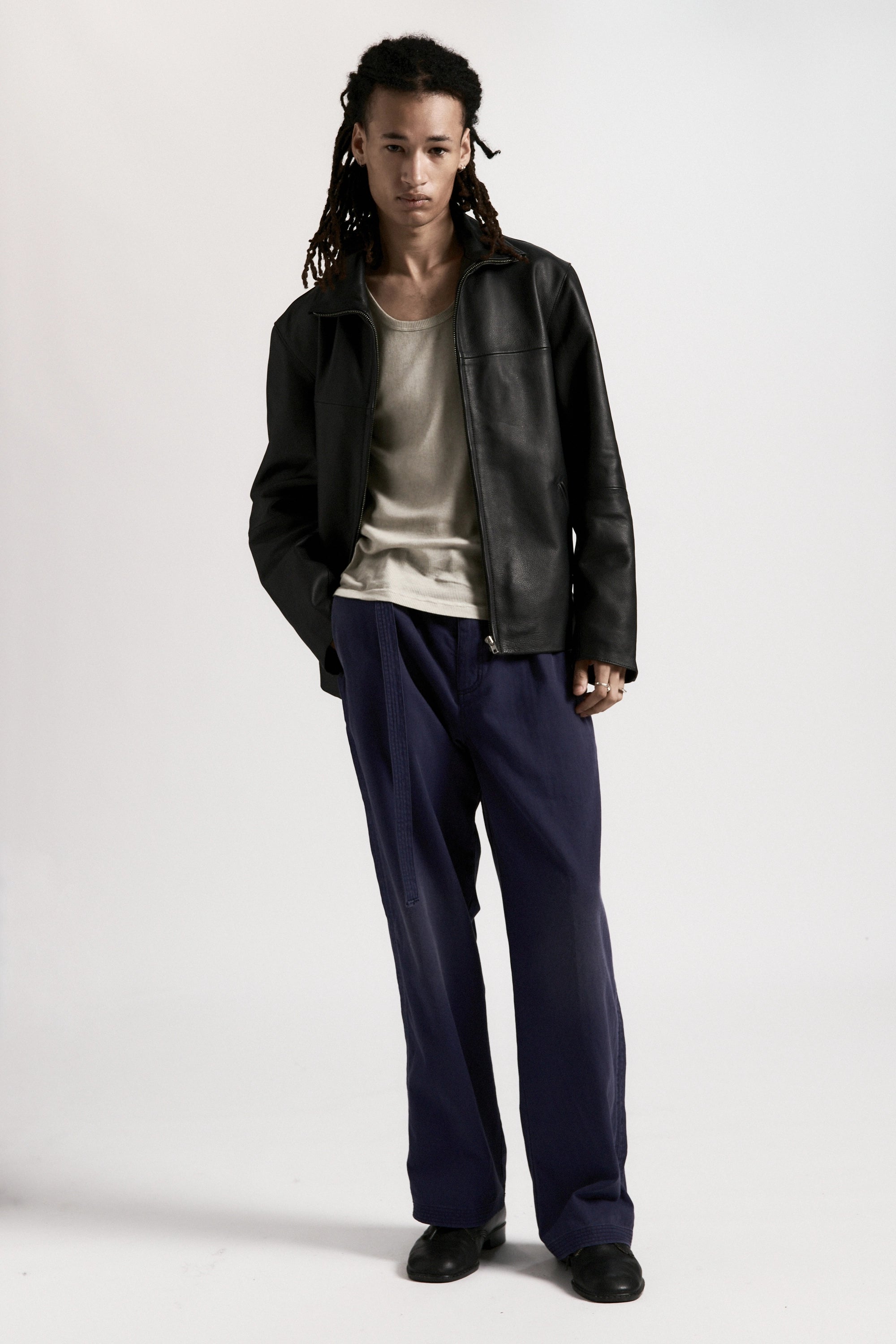Person wearing the black leather Bank Jacket, white shirt and navy pants on a white background