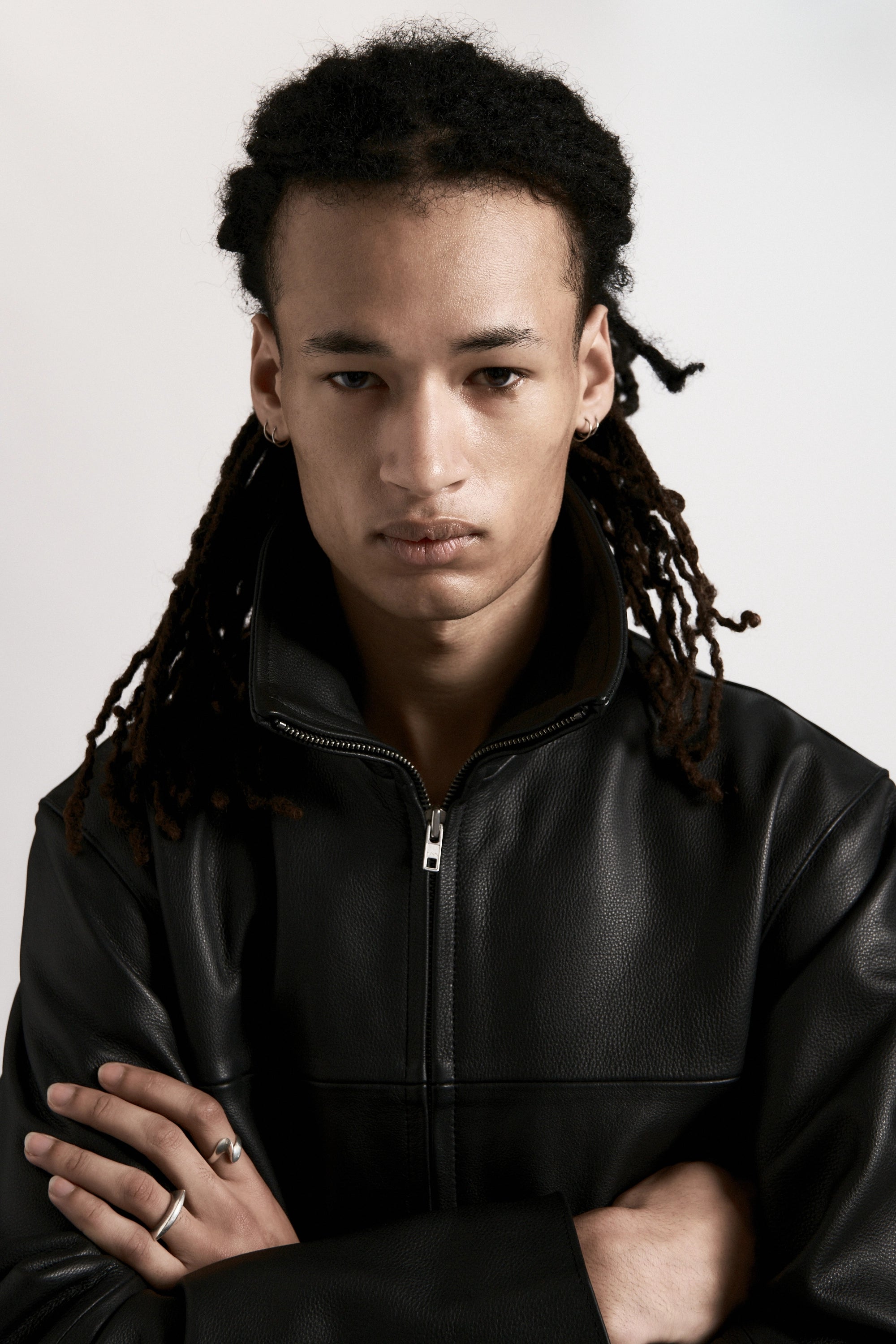 Person wearing a black leather zip up jacket against a plain background
