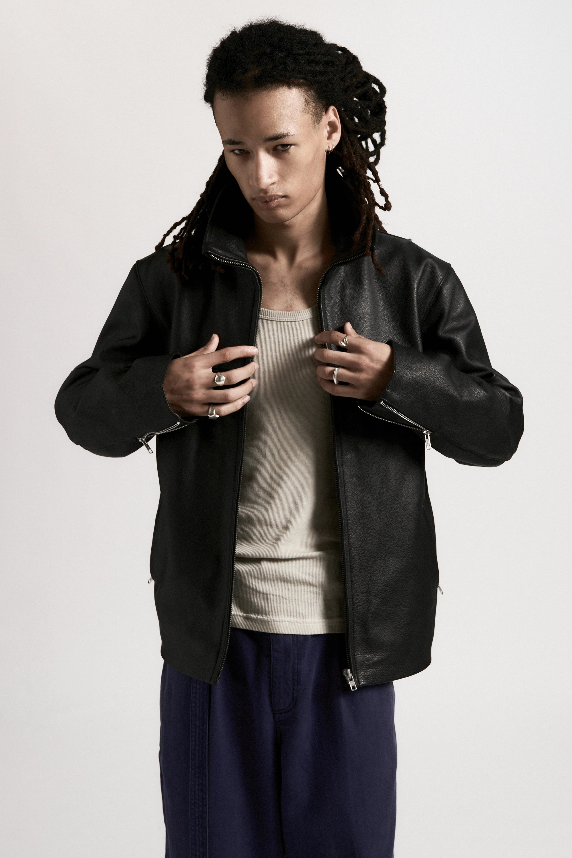 Person wearing a black leather jacket over a white shirt on a light gray background