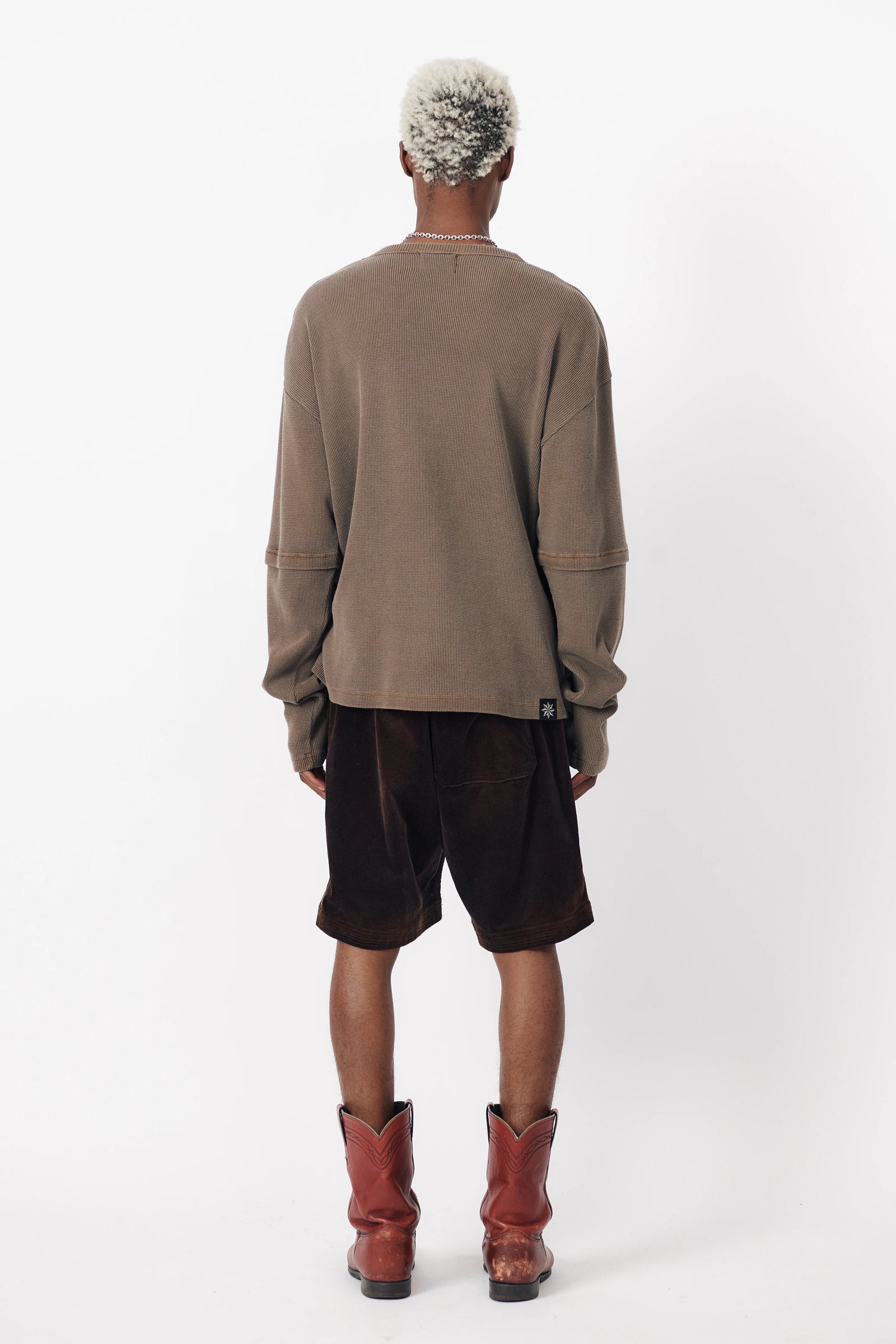 A person with their back turned to the camera wearing a pair of Beach Brains Washed Brown Baggy Shorts