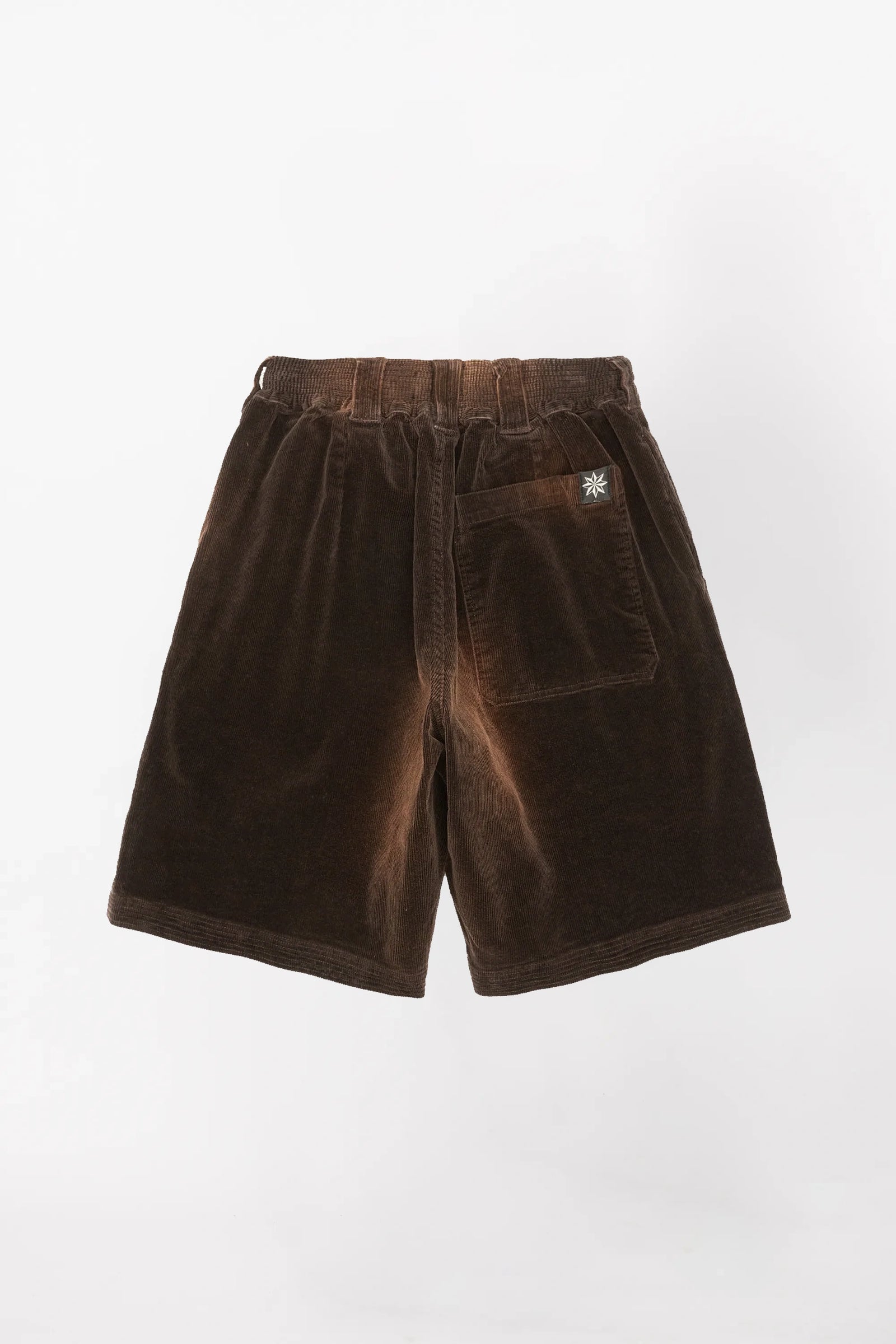 View from behind of a pair of brown corduroy baggy shorts  in a washed brown colour with an elastic waistband 