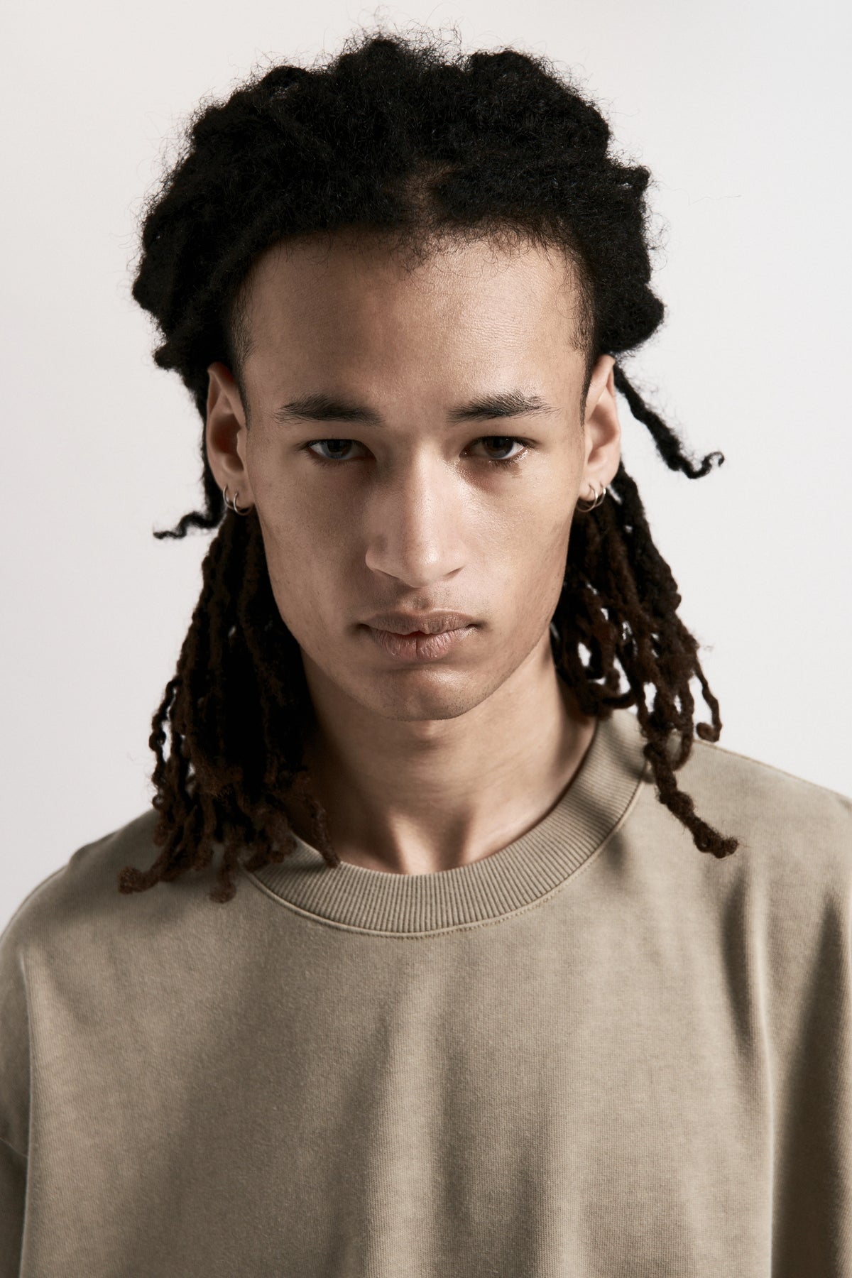 Person with styled dreadlocks wearing a Desert Dream T-Shirt against a plain background