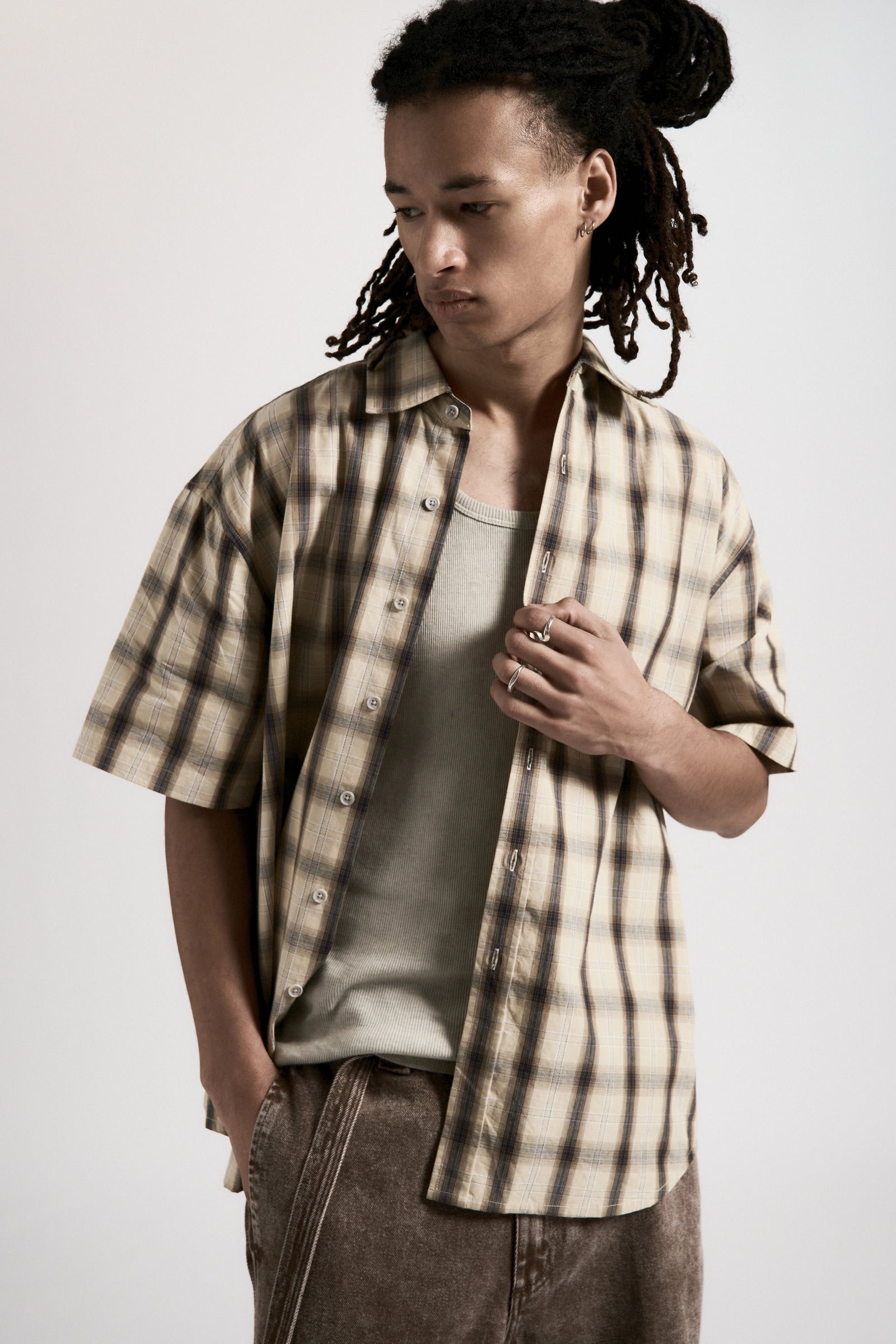 Person wearing a plaid shirt over a t-shirt with a plain background