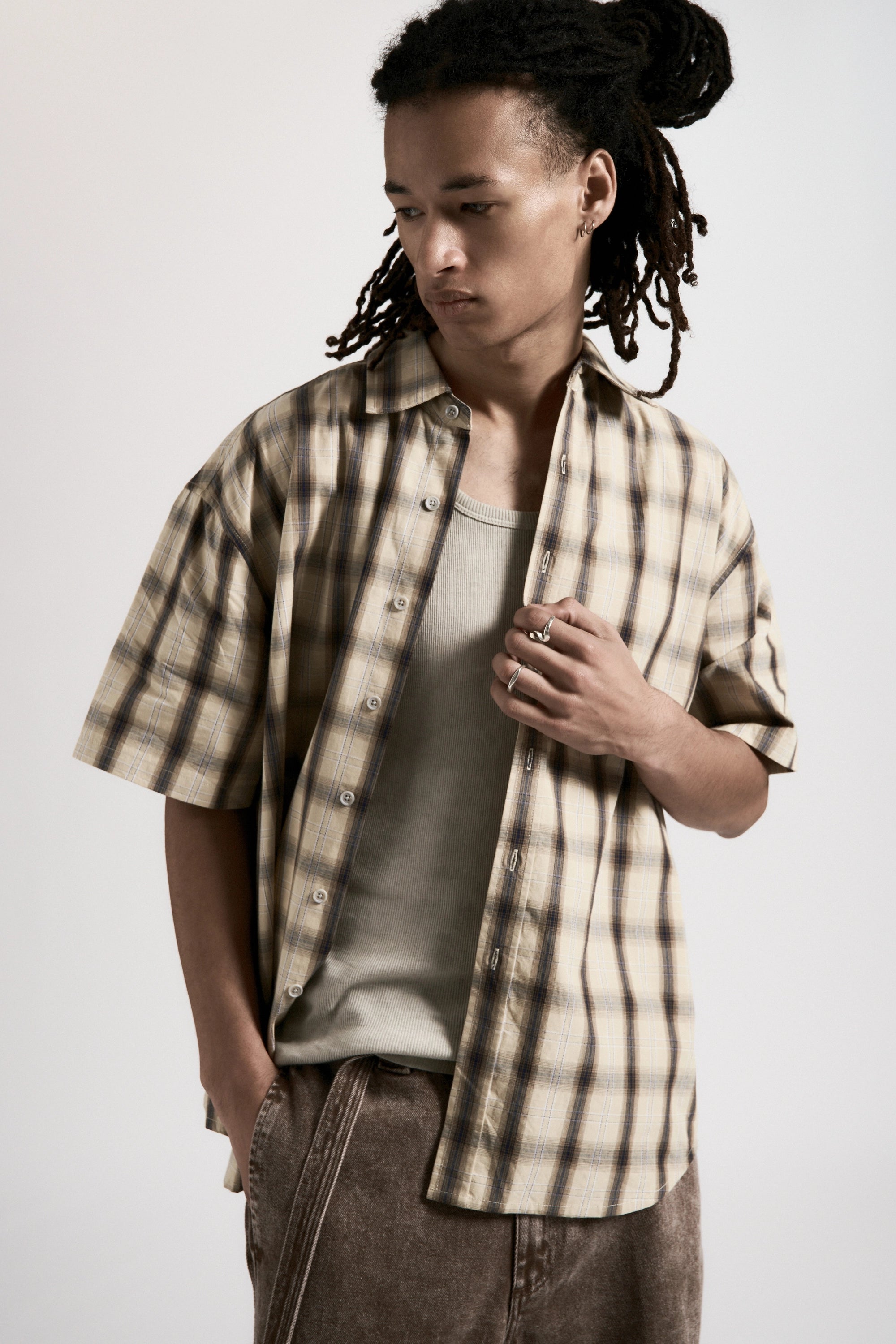 Person wearing a plaid shirt over a t-shirt with a plain background