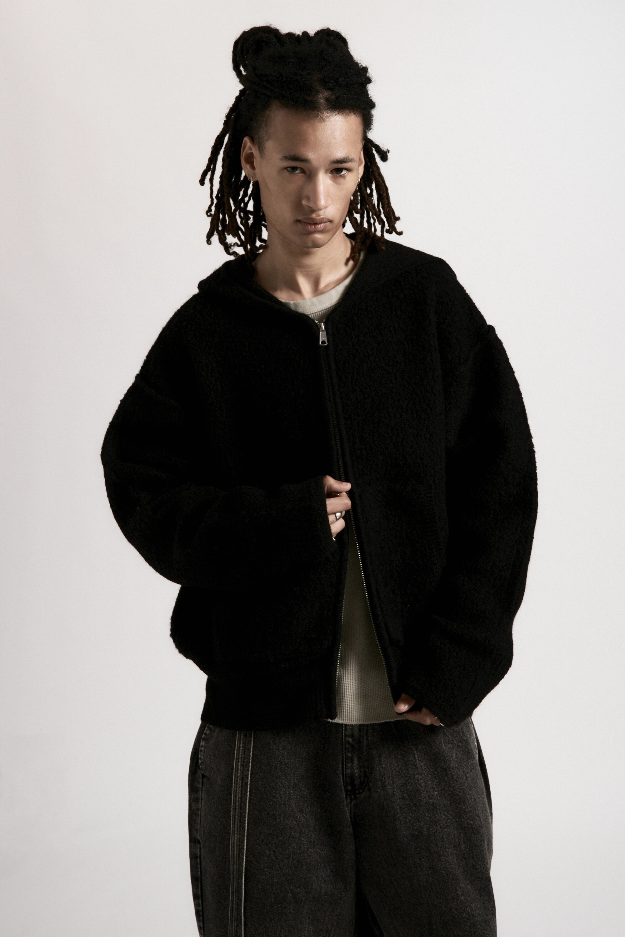 A male model wearing a black zipped hoodie on a white background