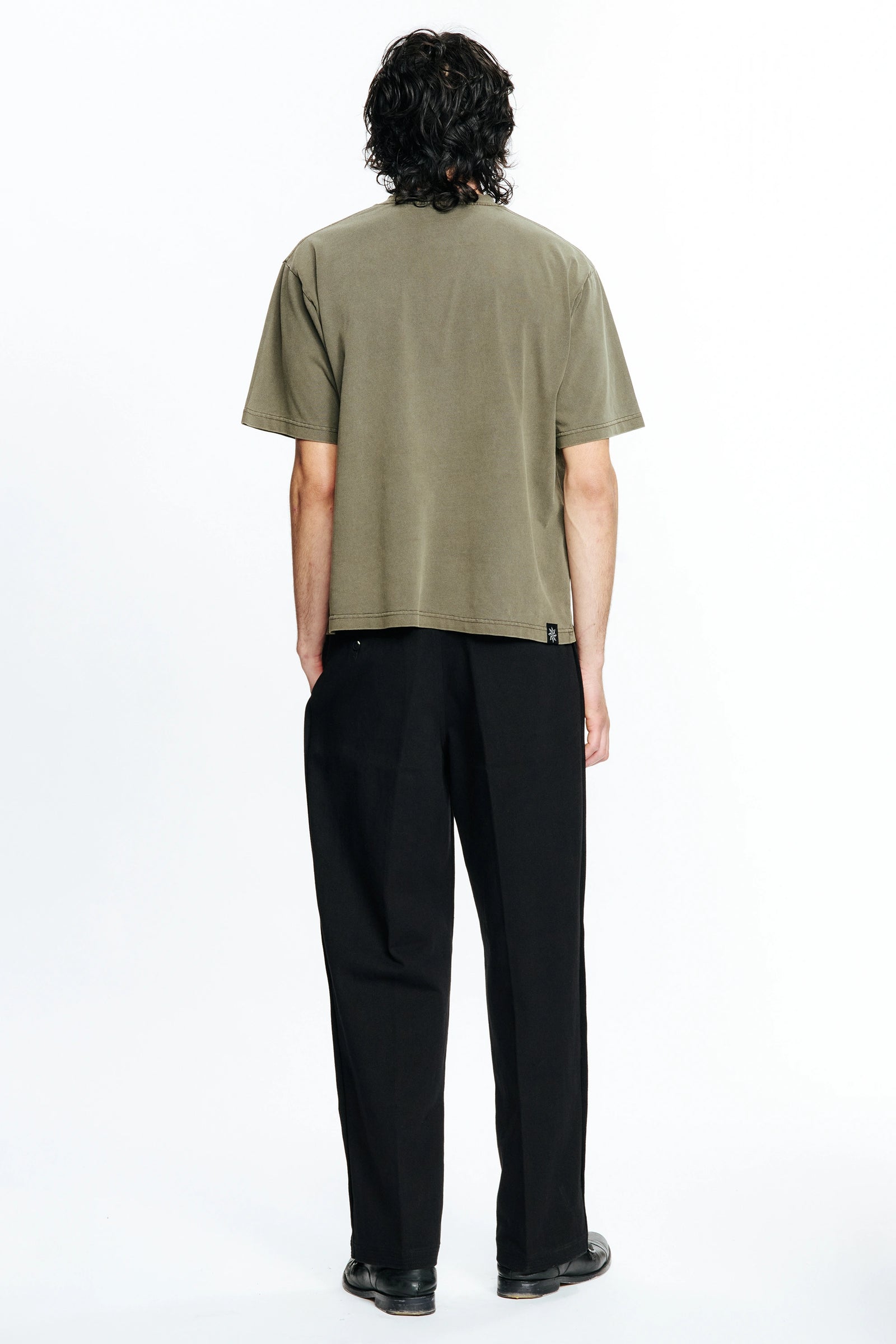 Person wearing a green t-shirt and black pants on a white background