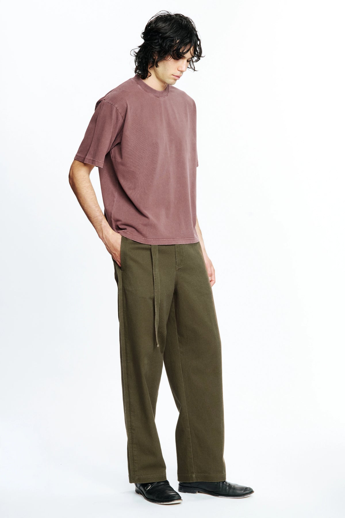 Person wearing a mauve t-shirt and olive green pants on a white background