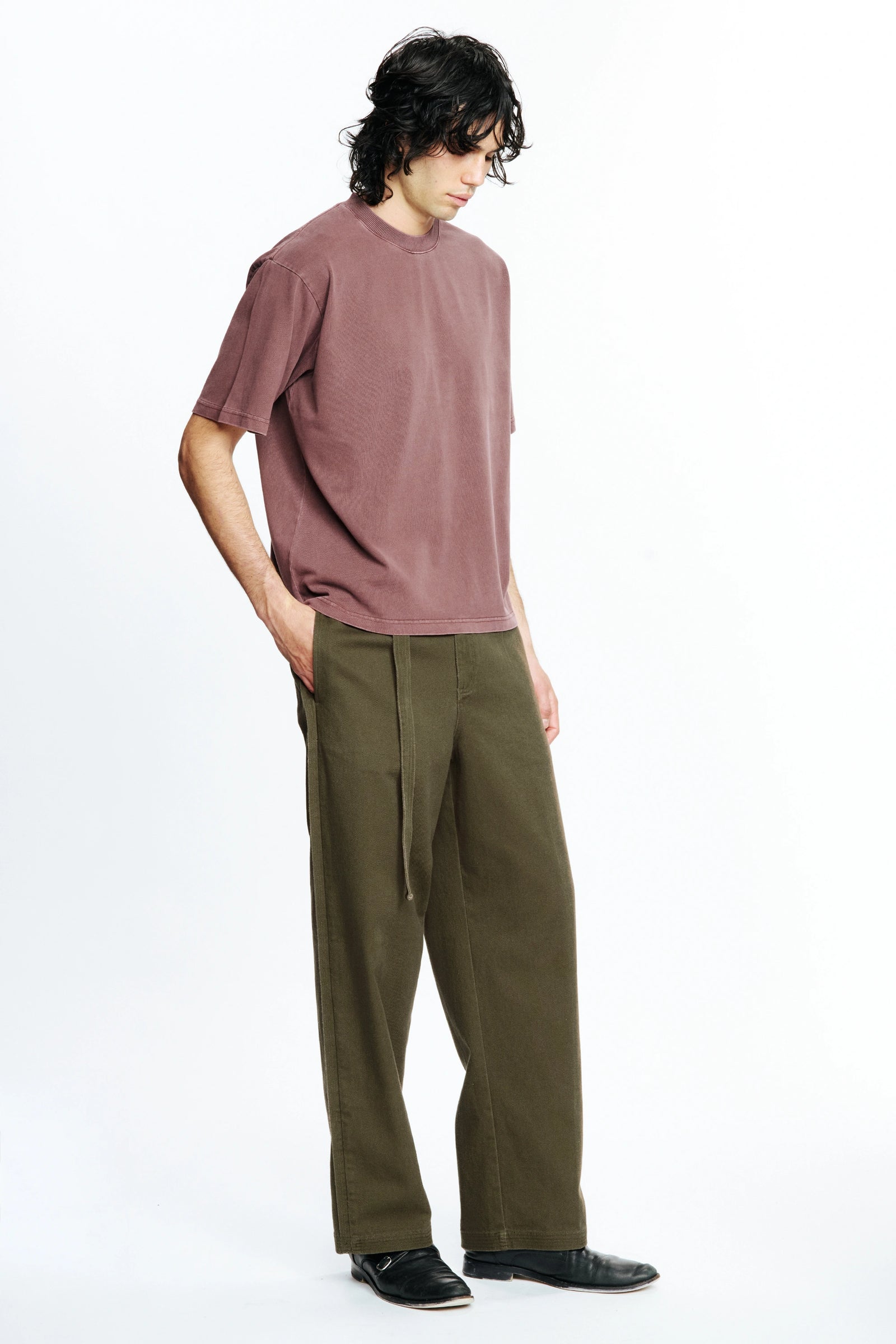 Person wearing a mauve t-shirt and olive green pants on a white background