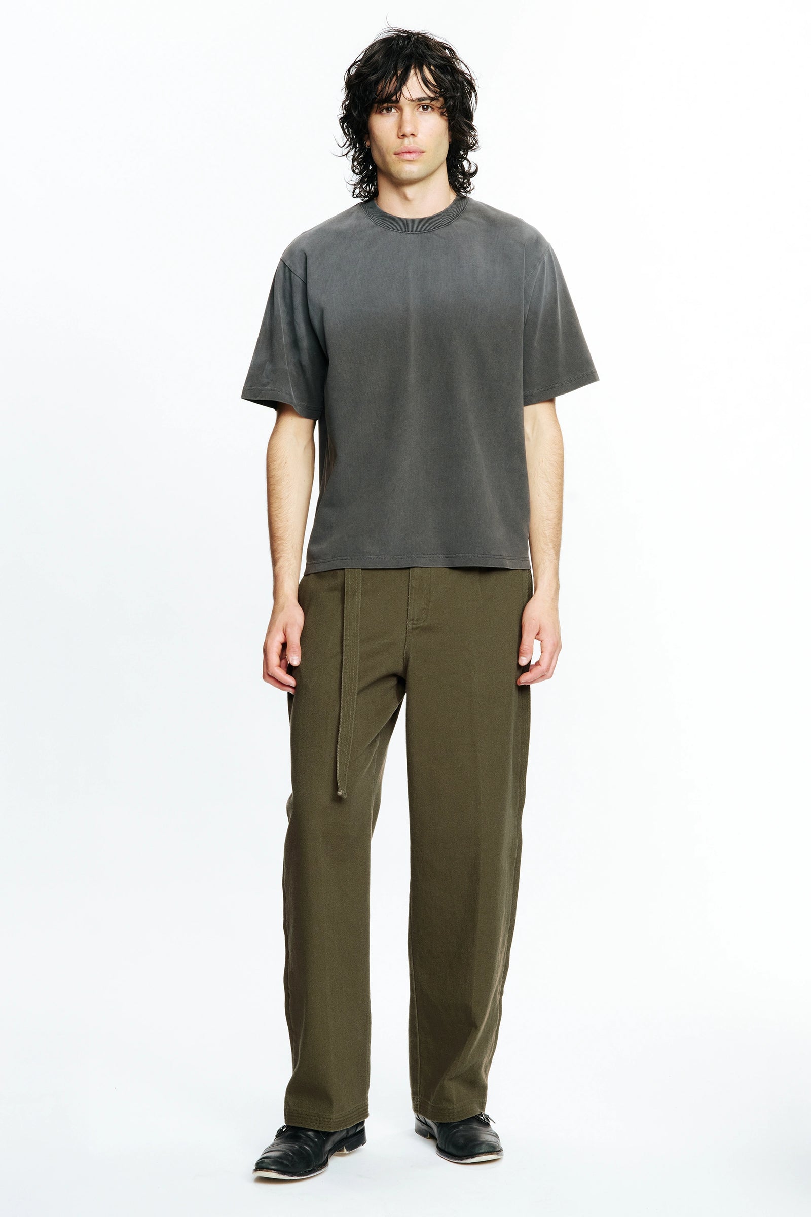 Person wearing a Sun Faded Black Dream T-Shirt and olive green pants on a white background