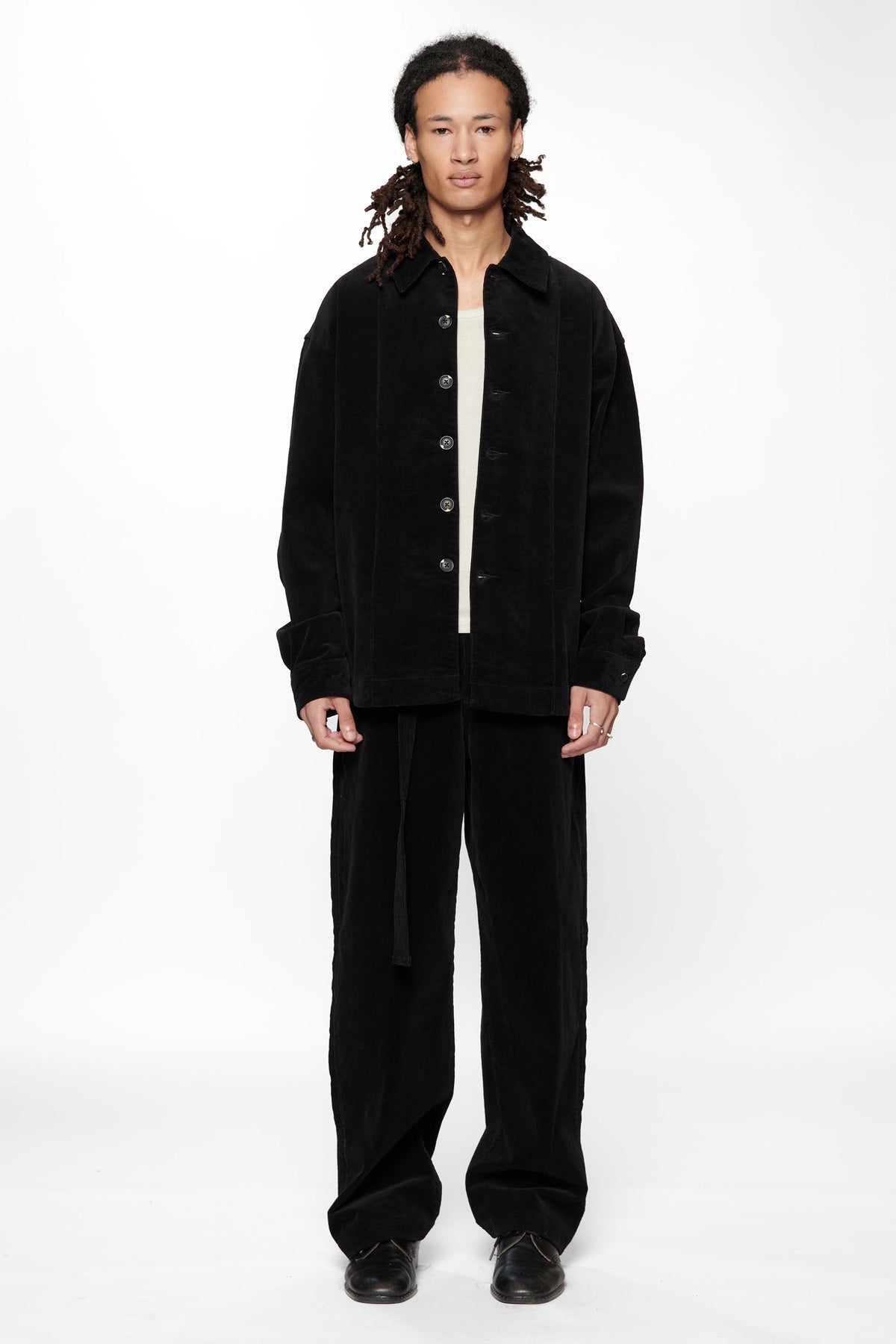 A male model wearing a Vintage Black Corduroy Float Overshirt with dark trousers on a white background