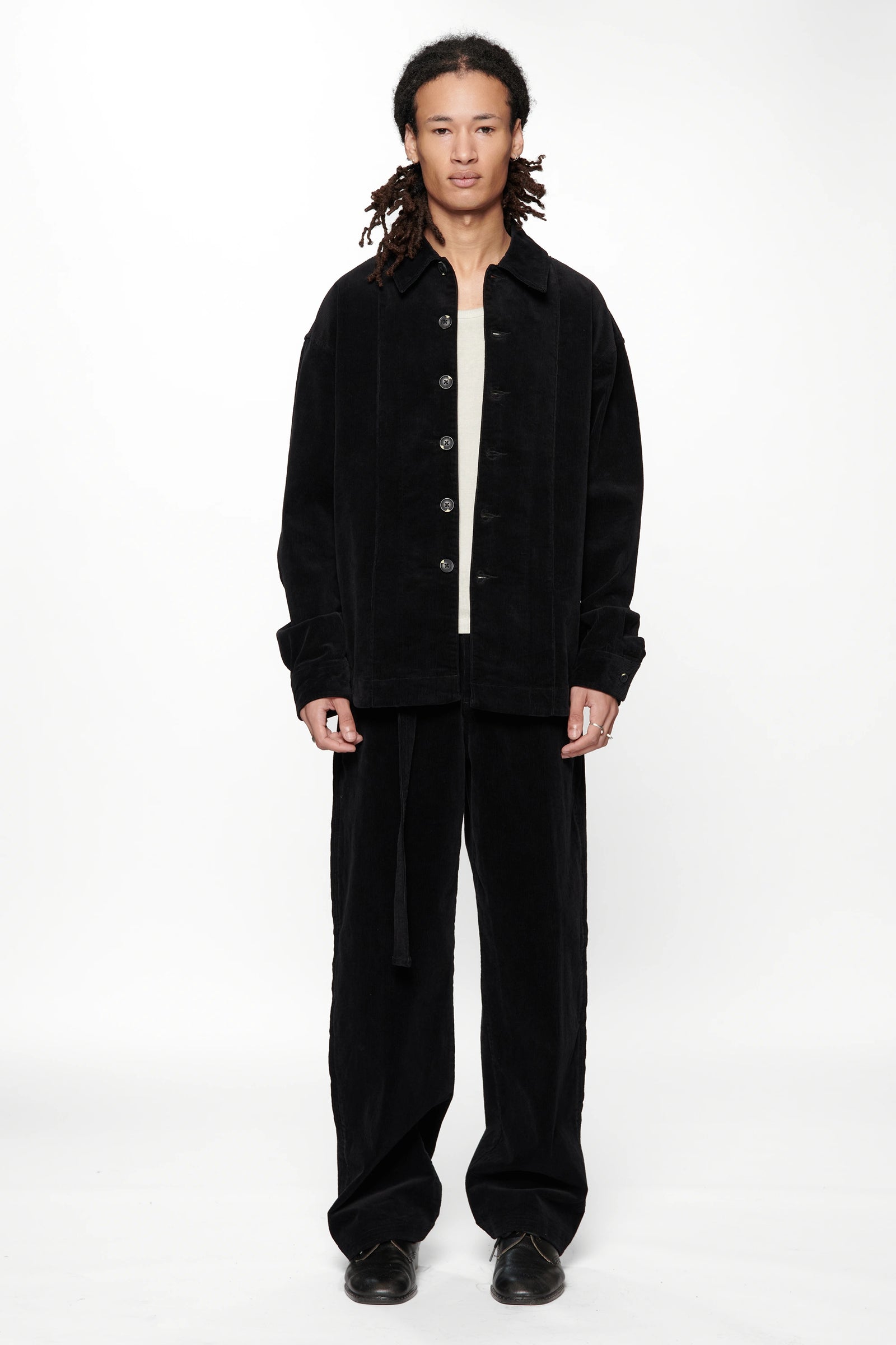 A male model wearing a Vintage Black Corduroy Float Overshirt with dark trousers on a white background