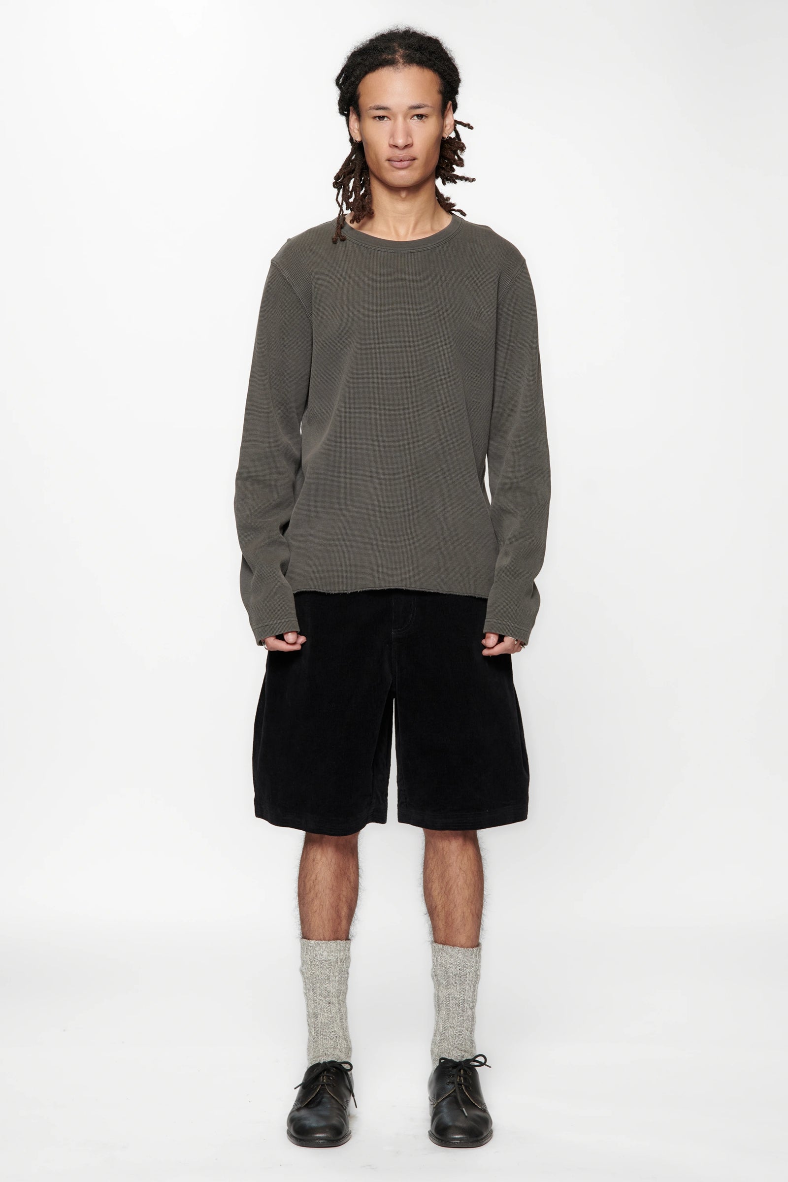 Person wearing a grey sweater and Vintage Black Corduroy Hang Shorts on a white background