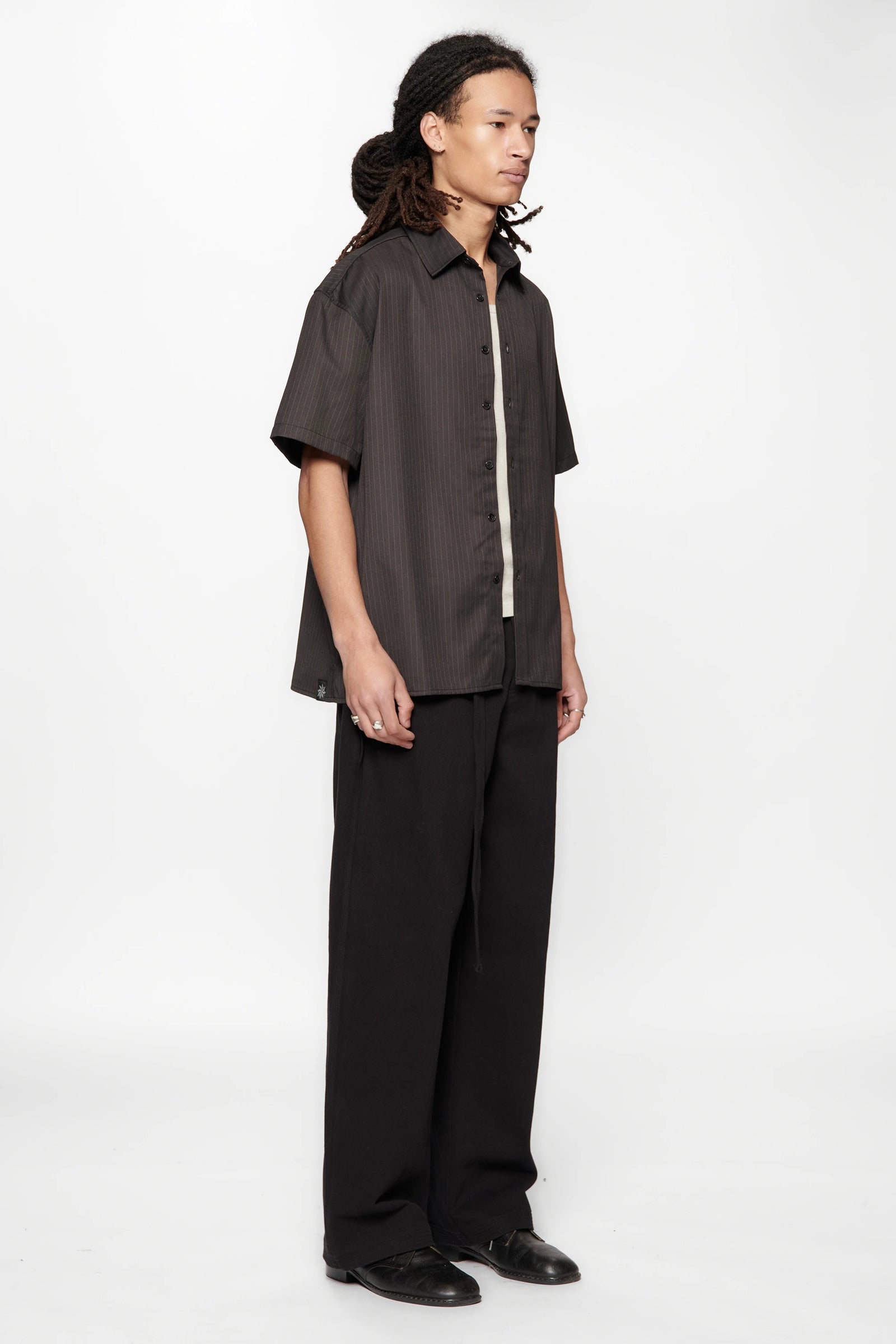 Person wearing a dark shirt and black pants on a white background