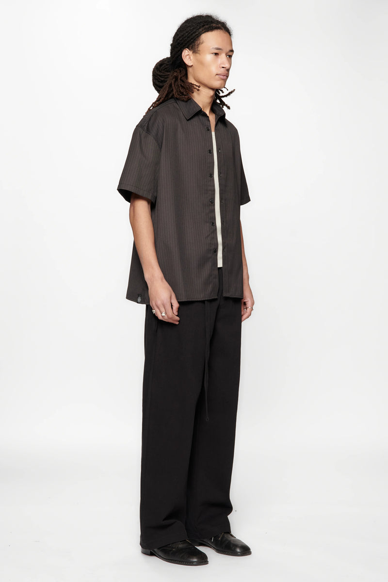 Person wearing a dark shirt and black pants on a white background
