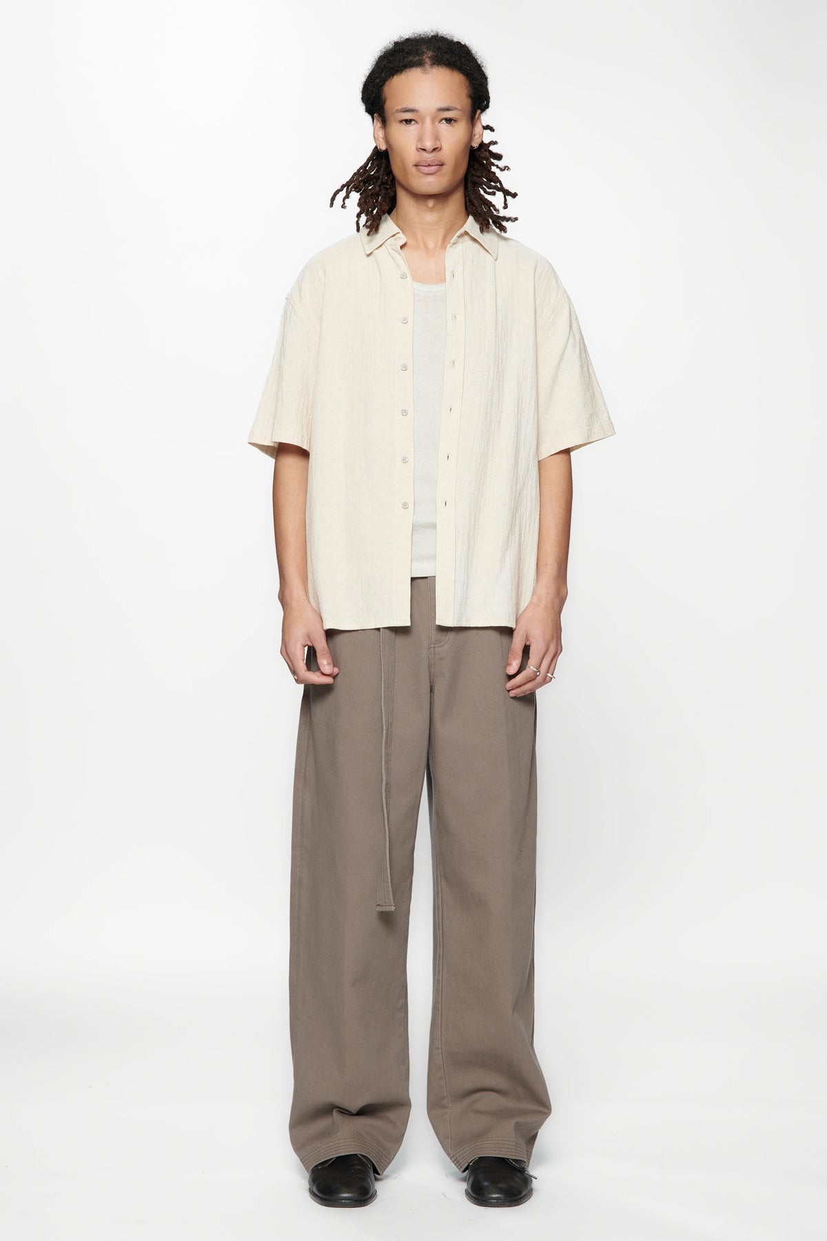 Person wearing the Hold SS Shirt in Off White and brown pants on a white background