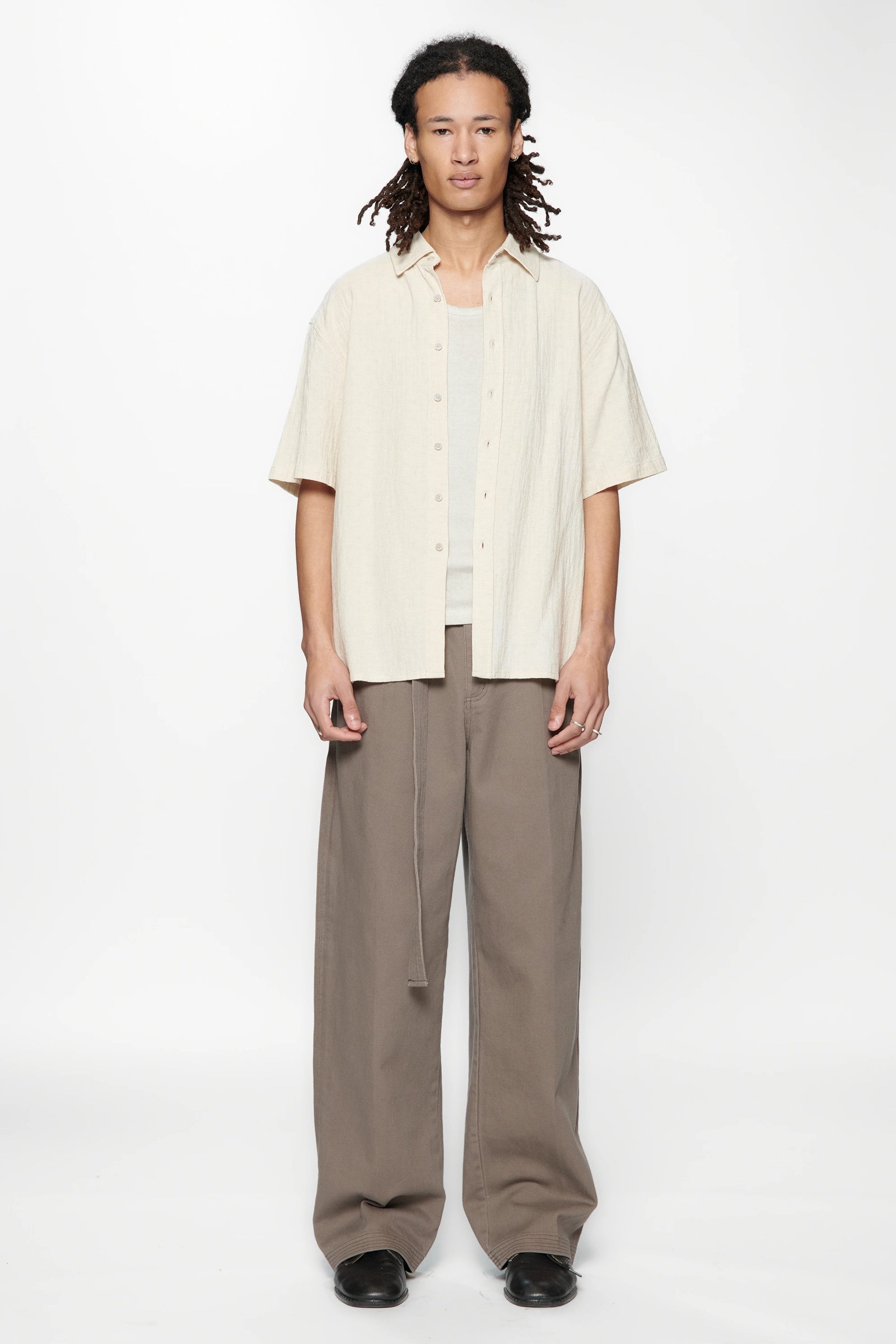 Person wearing the Hold SS Shirt in Off White and brown pants on a white background