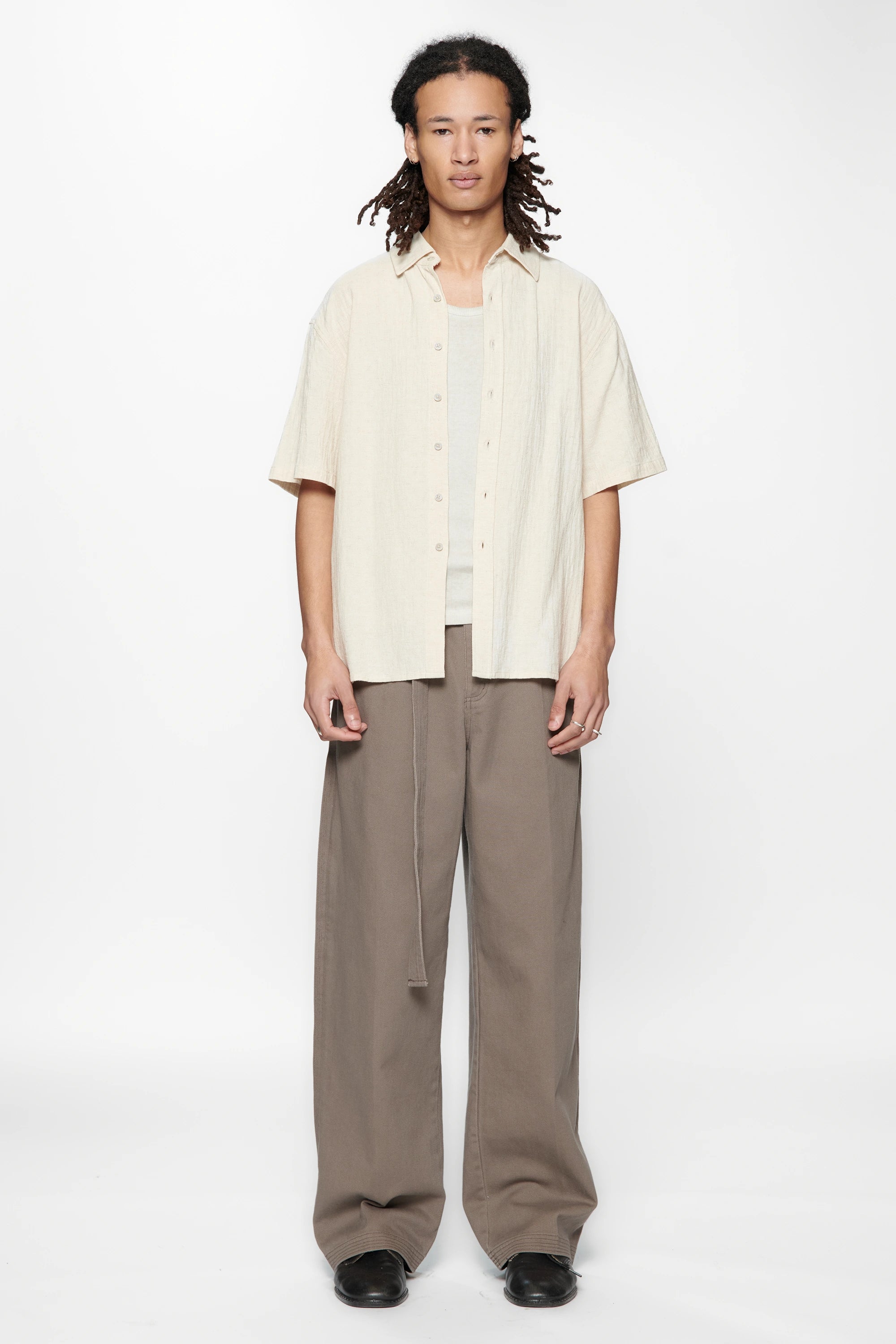 Person wearing the Hold SS Shirt in Off White and brown pants on a white background