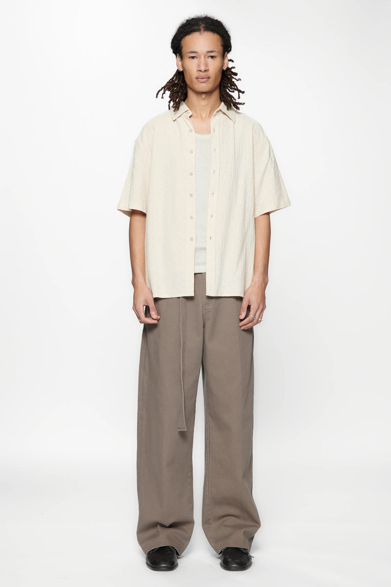 Person wearing the Hold SS Shirt in Off White and brown pants on a white background
