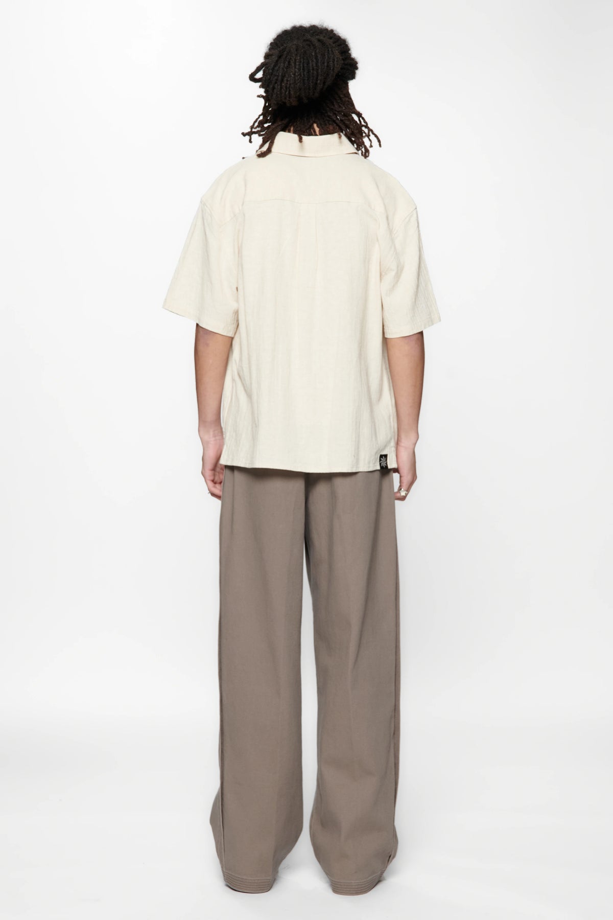 Behind view of a person wearing the Hold SS Shirt in Off White and brown pants