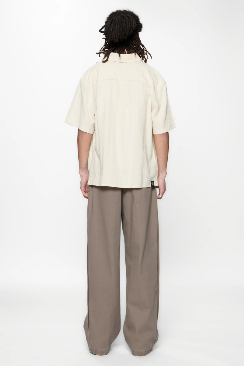 Behind view of a person wearing the Hold SS Shirt in Off White and brown pants