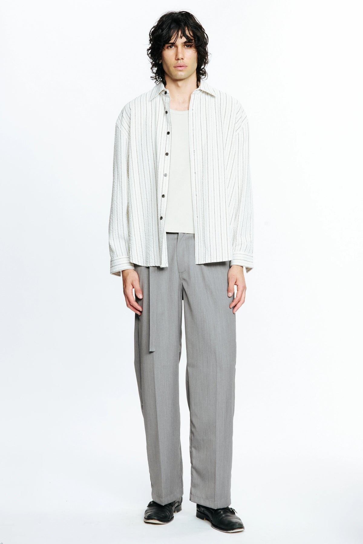 Person wearing a white striped long-sleeve shirt and grey pants on a white background