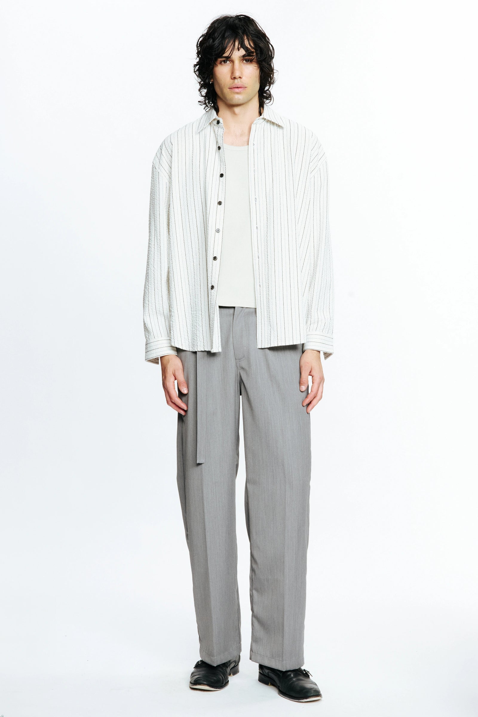 Person wearing a white striped long-sleeve shirt and grey pants on a white background