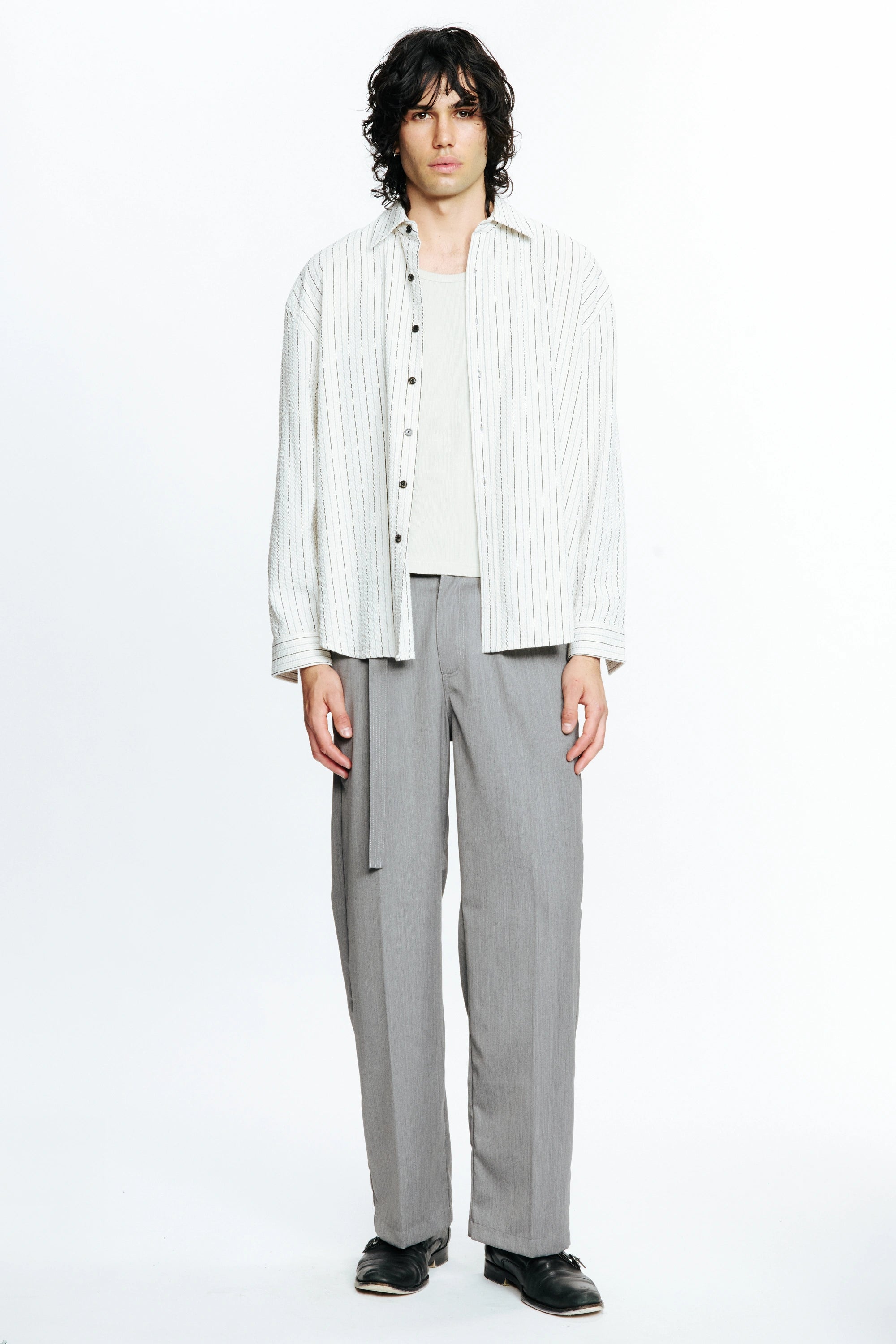 Person wearing a white striped long-sleeve shirt and grey pants on a white background