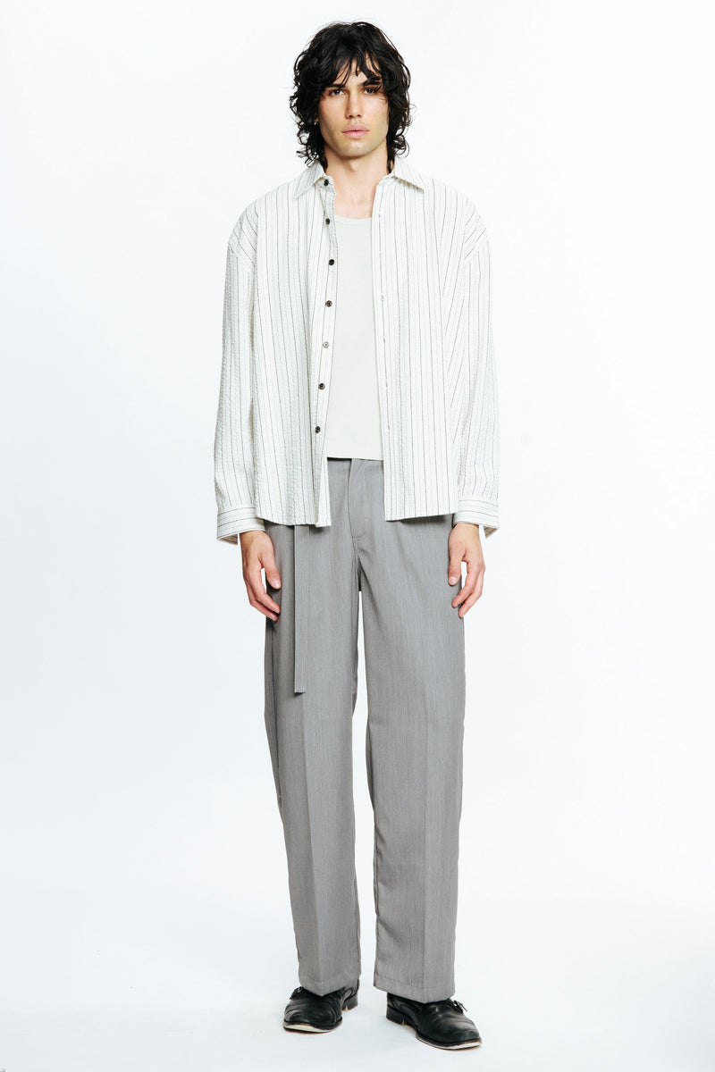 Person wearing a white striped long-sleeve shirt and grey pants on a white background