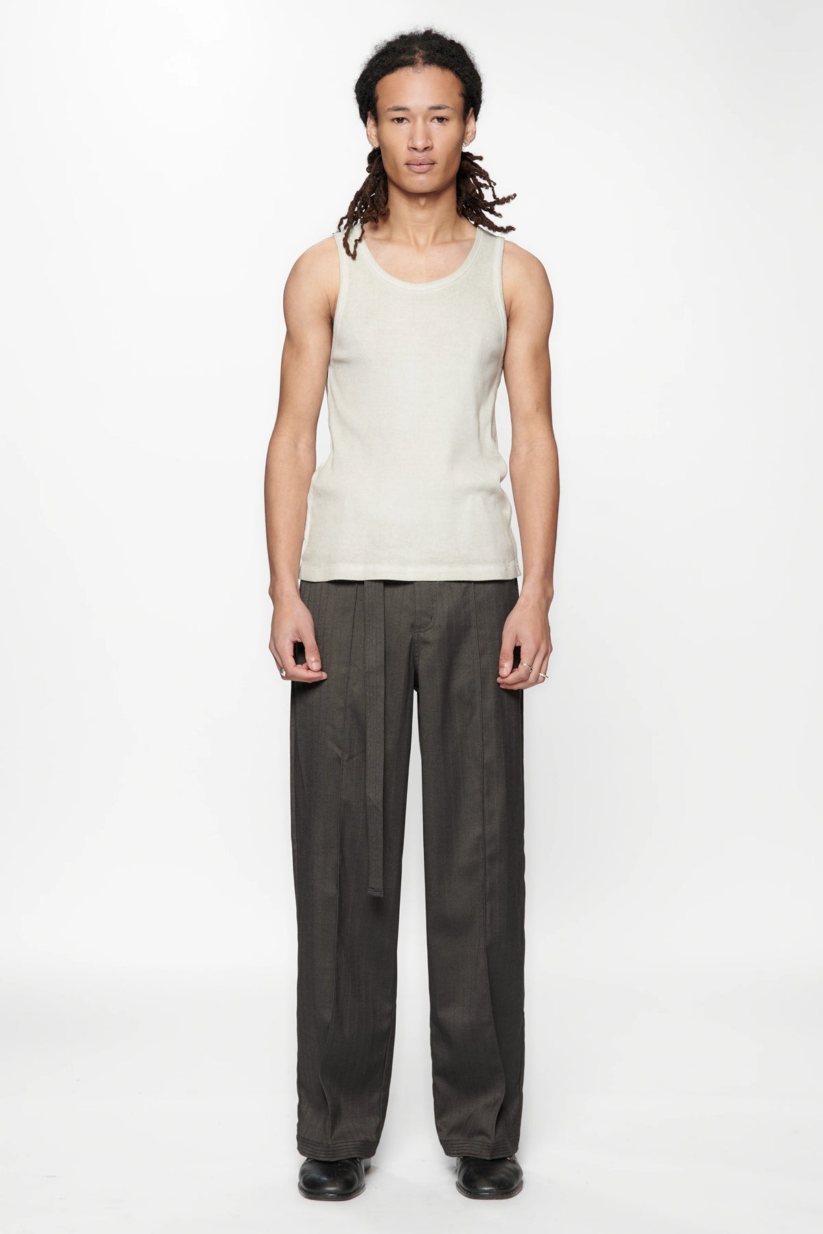 Person wearing a light-colored sleeveless top and the Shadow Suit Pants Black Herringbone by Beach Brains