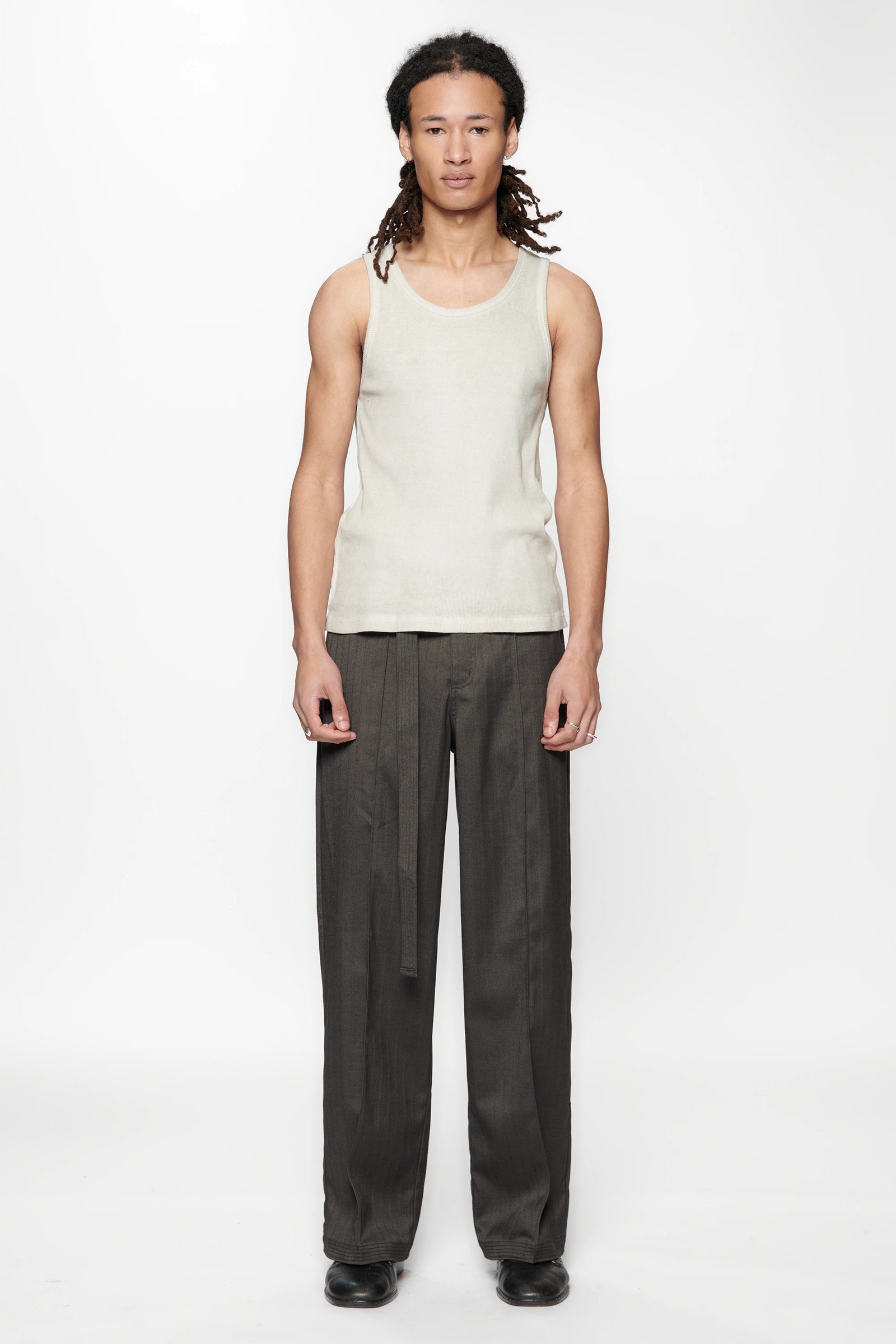 Person wearing a light-colored sleeveless top and the Shadow Suit Pants Black Herringbone by Beach Brains