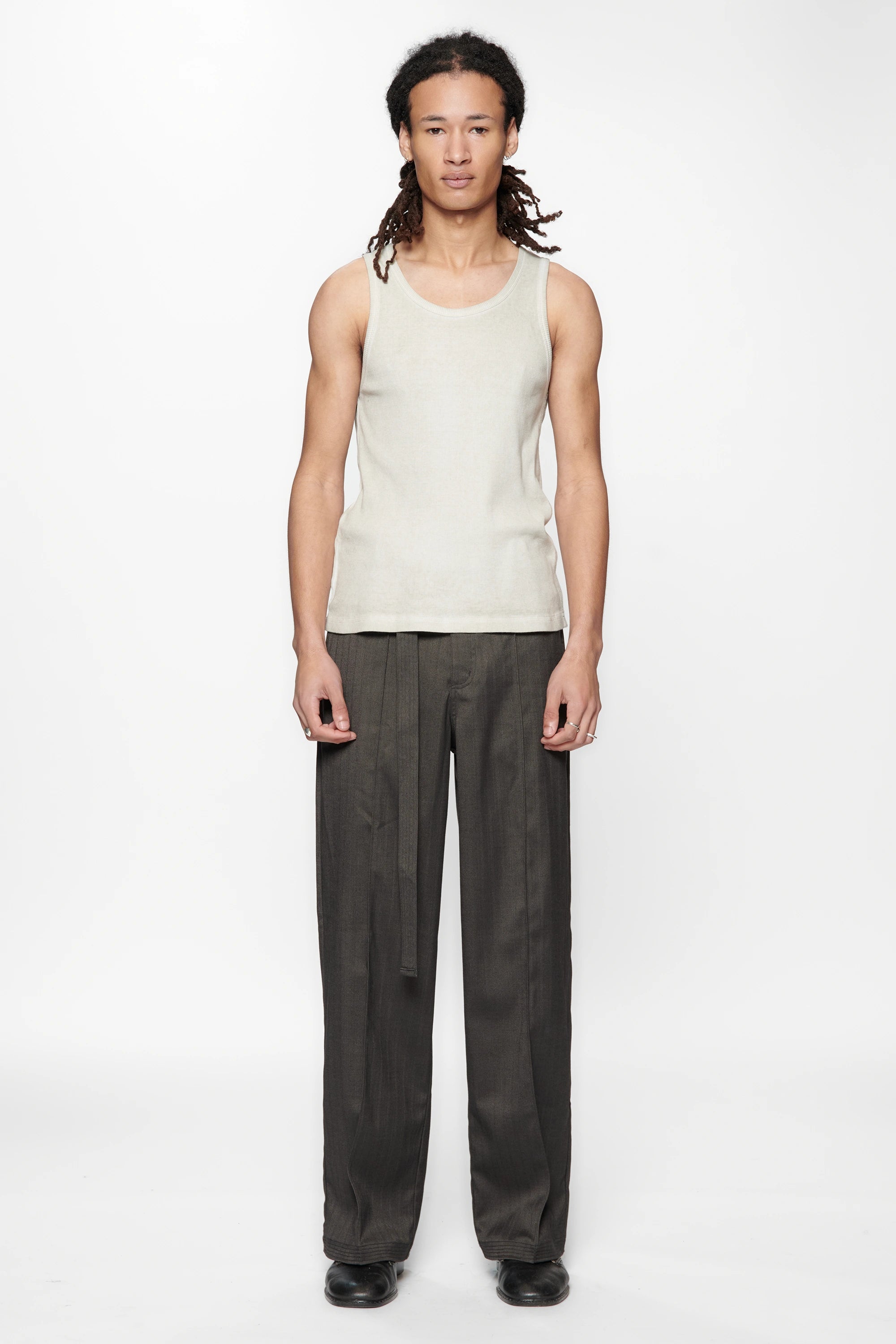 Person wearing a light-colored sleeveless top and the Shadow Suit Pants Black Herringbone by Beach Brains