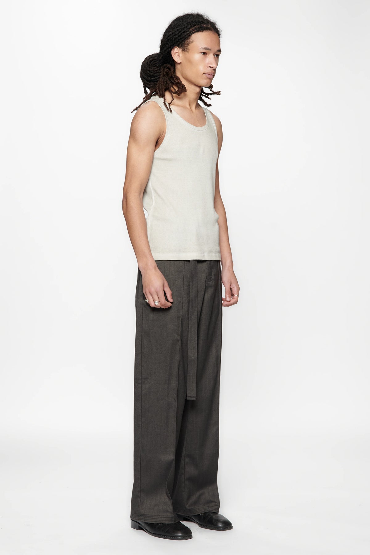 Side view of a person wearing a light-colored sleeveless top and the Shadow Suit Pants Black Herringbone by Beach Brains