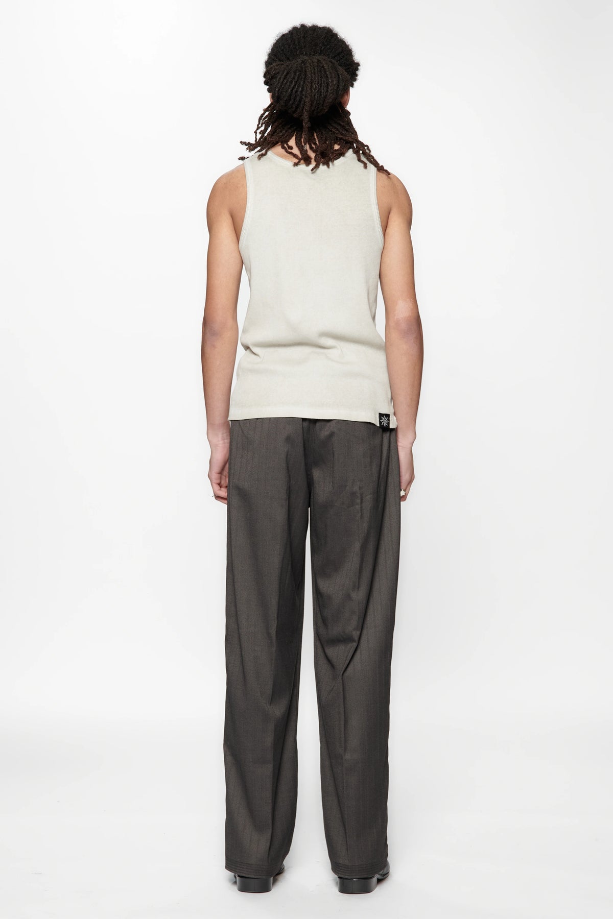 Rear view of a person wearing a light-colored sleeveless top and the Shadow Suit Pants Black Herringbone by Beach Brains