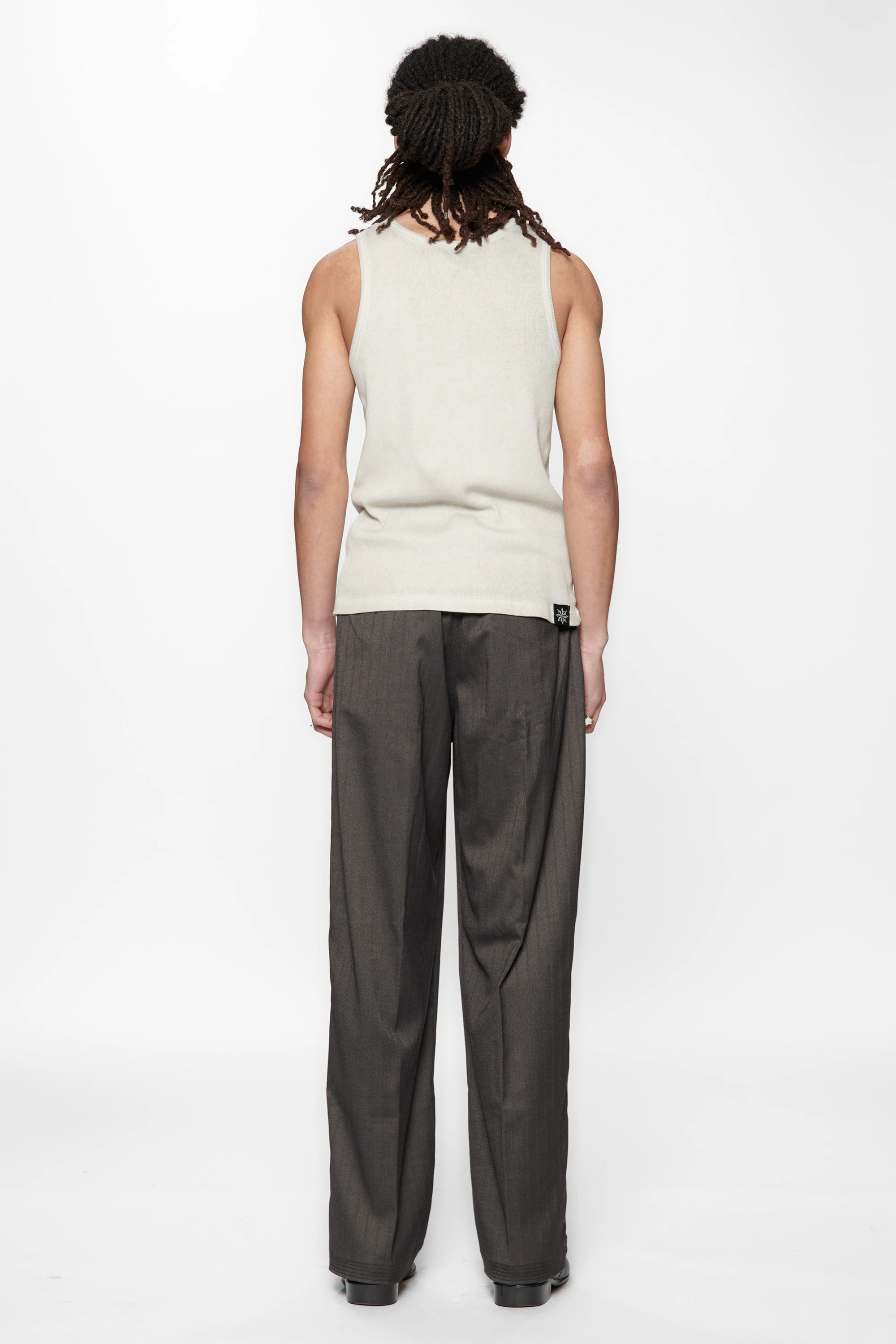 Rear view of a person wearing a light-colored sleeveless top and the Shadow Suit Pants Black Herringbone by Beach Brains