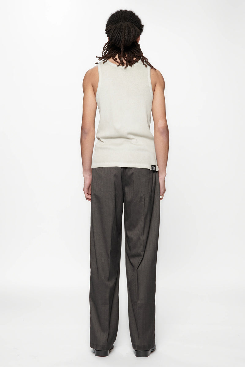 Rear view of a person wearing a light-colored sleeveless top and the Shadow Suit Pants Black Herringbone by Beach Brains