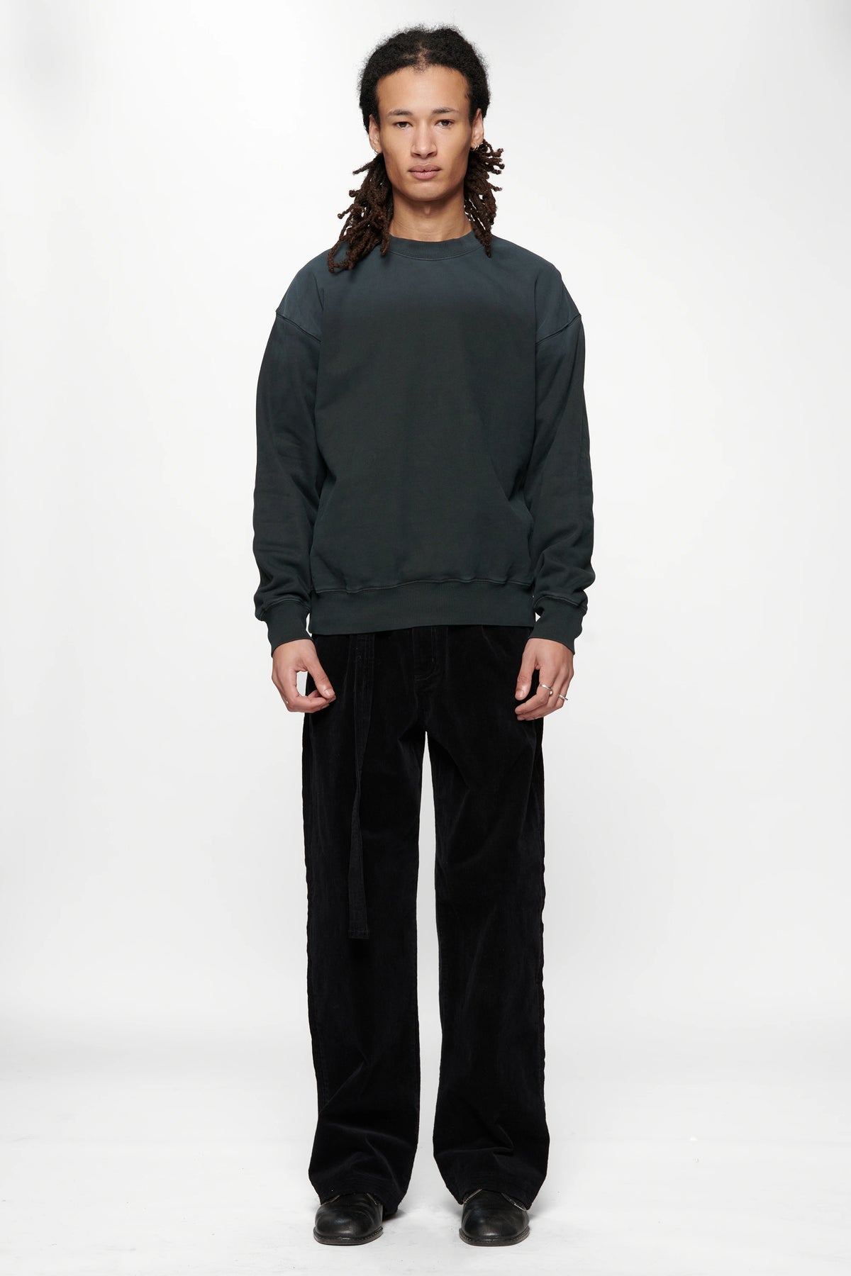 Person wearing a dark grey sweatshirt made from 420gsm brushed back fleece and black pants on a white background