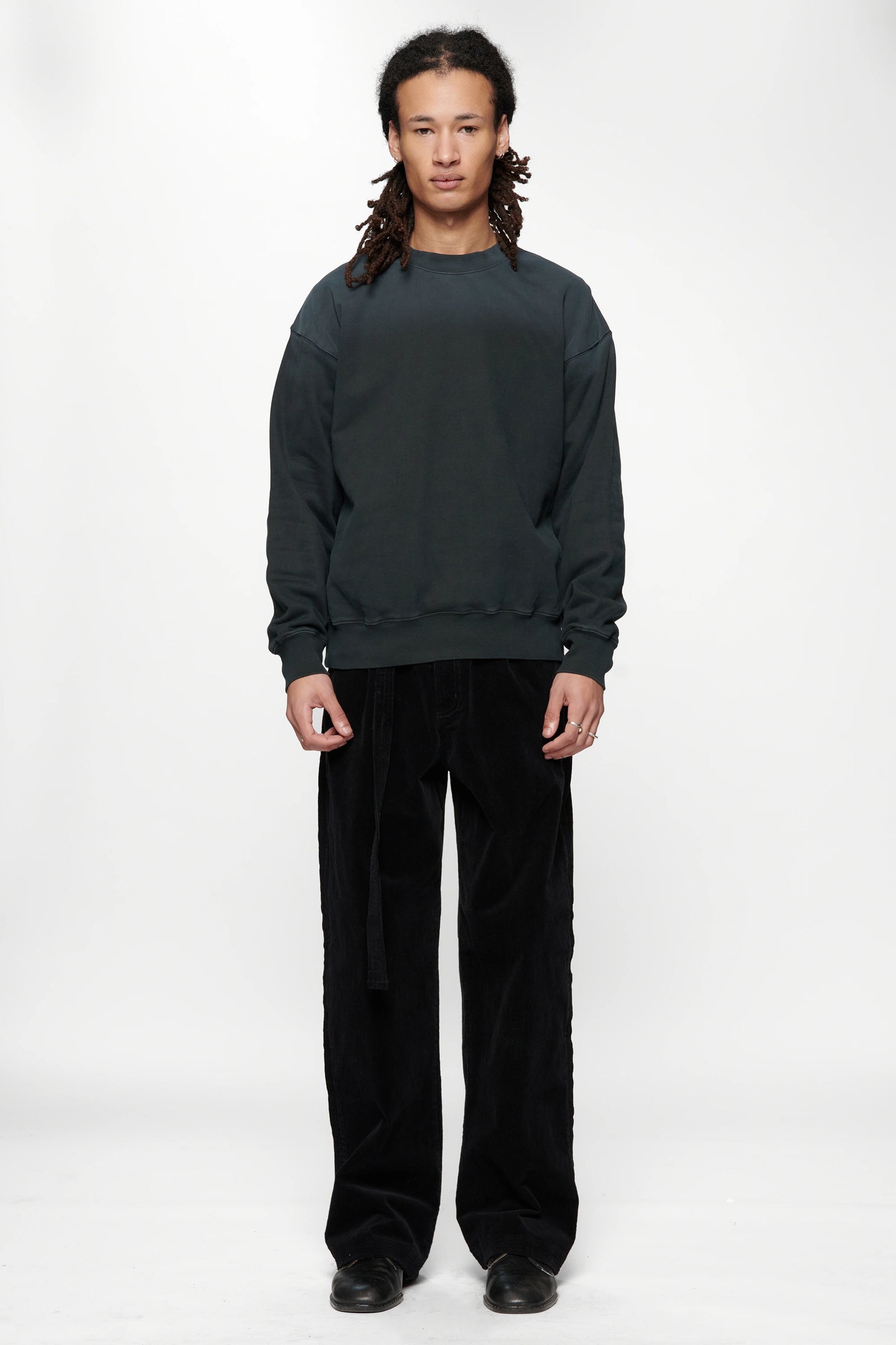 Person wearing a dark grey sweatshirt made from 420gsm brushed back fleece and black pants on a white background