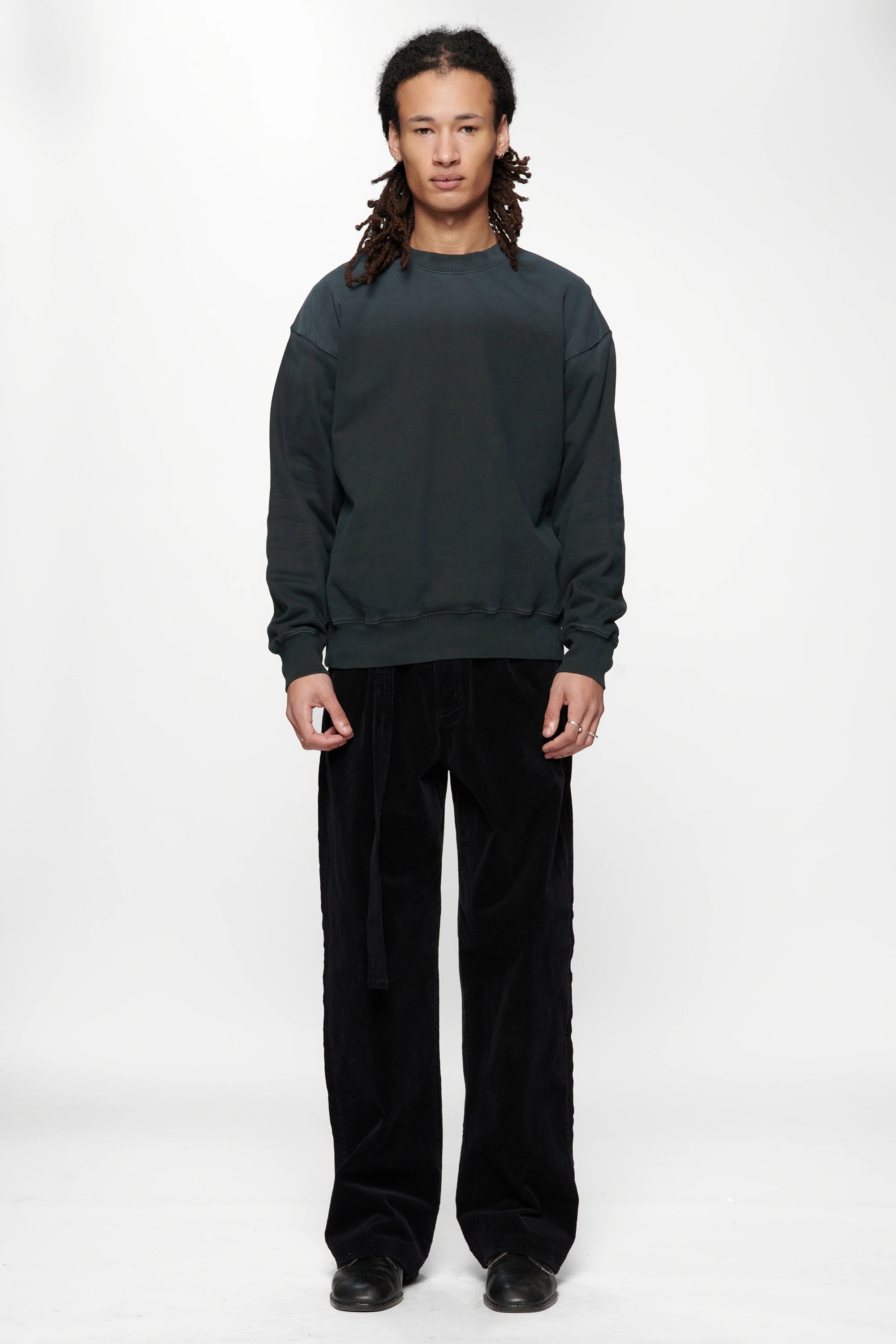 Person wearing a dark grey sweatshirt made from 420gsm brushed back fleece and black pants on a white background