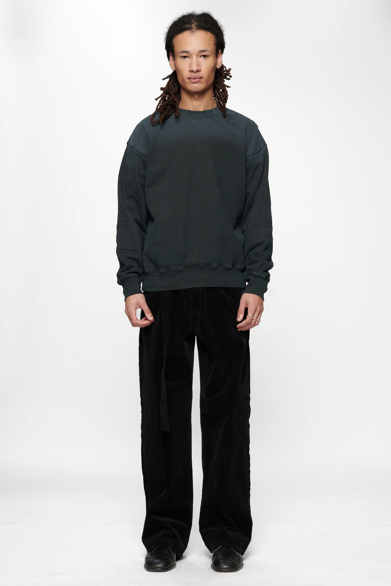 Person wearing a dark grey sweatshirt made from 420gsm brushed back fleece and black pants on a white background